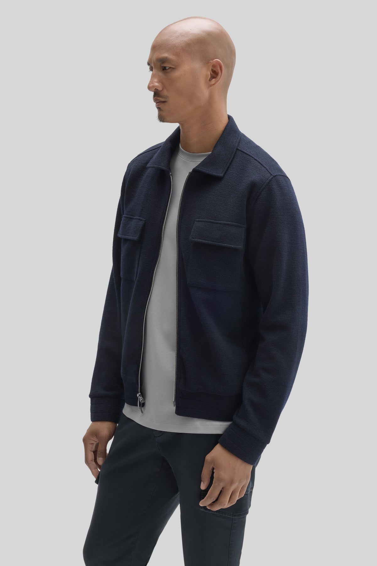Navy full zip jacket with front flap pockets and collar, worn over gray t-shirt.