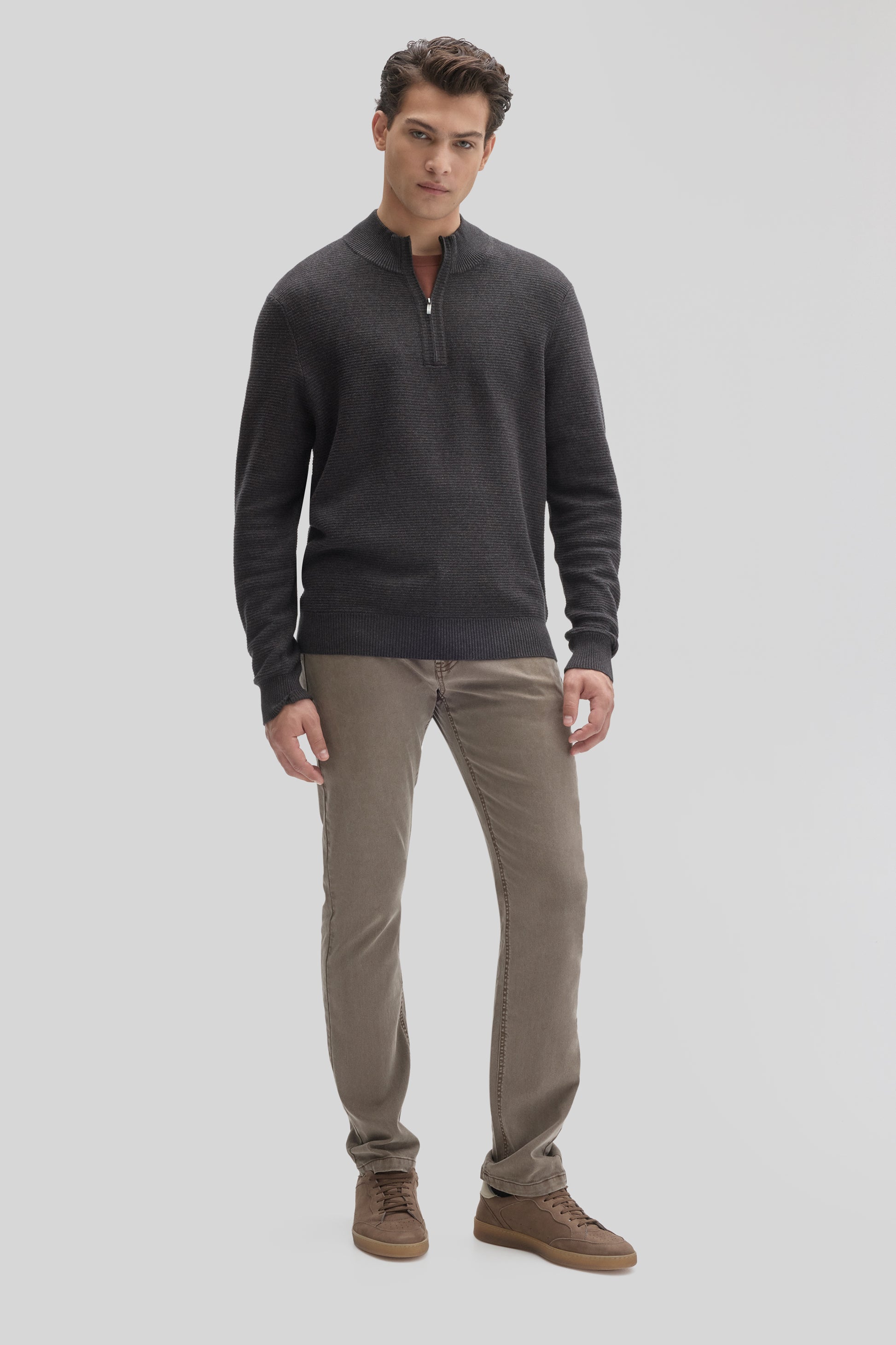 Man wearing charcoal quarter-zip sweater with textured knit, paired with beige pants and brown suede shoes.
