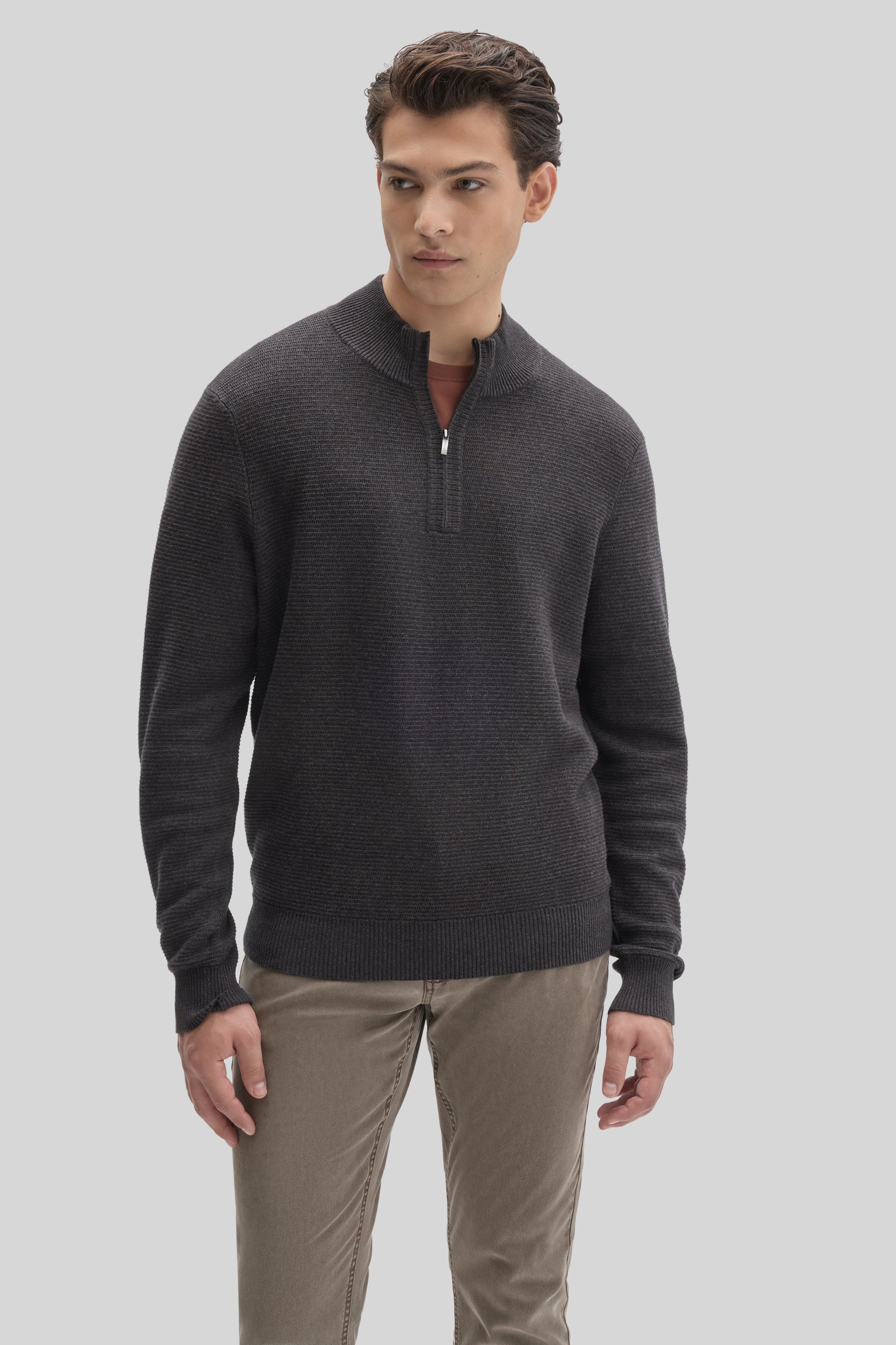 Man wearing charcoal gray quarter zip sweater with ribbed texture and beige pants.