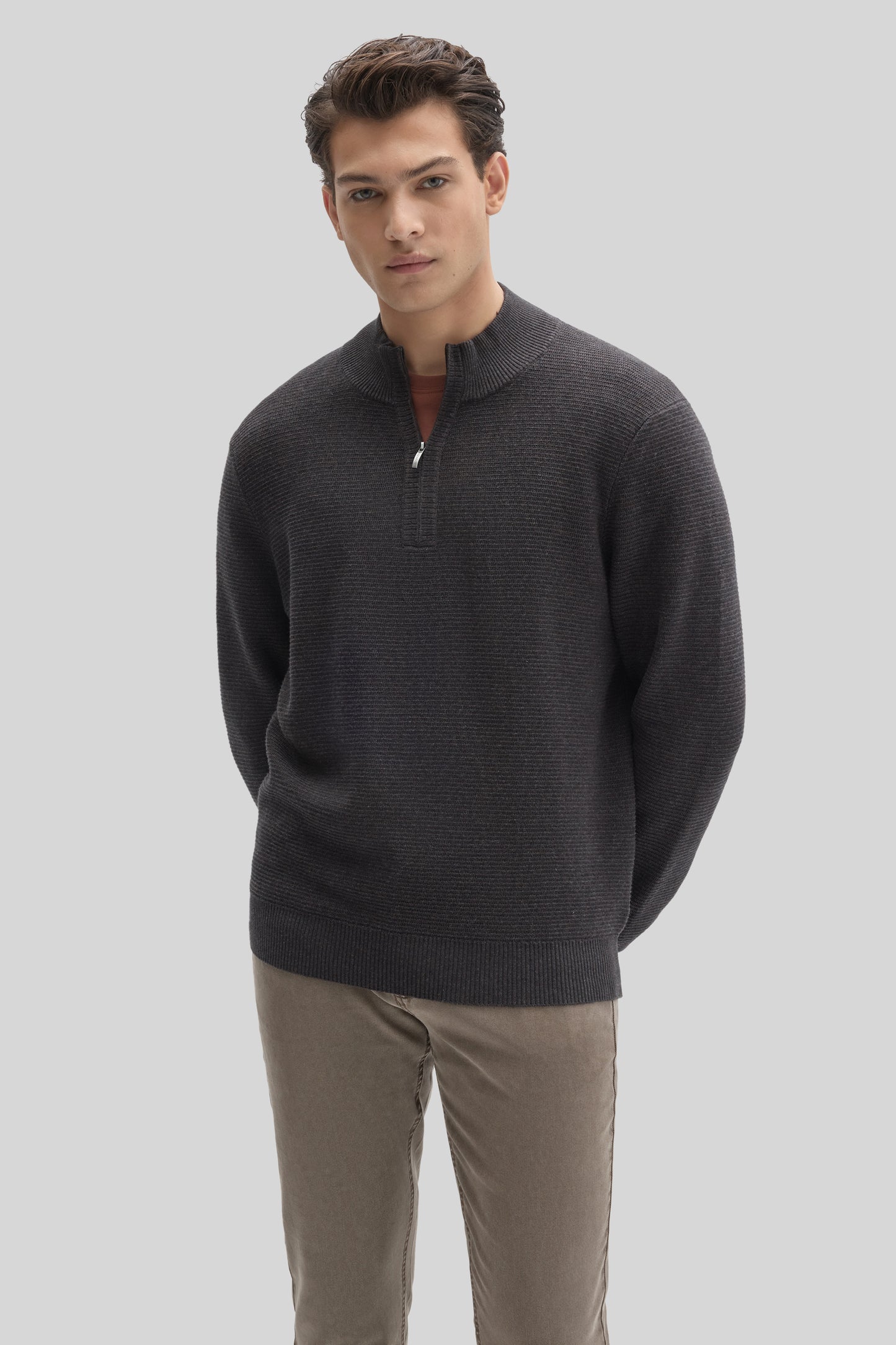 Charcoal quarter zip sweater with textured knit fabric worn with tan pants.