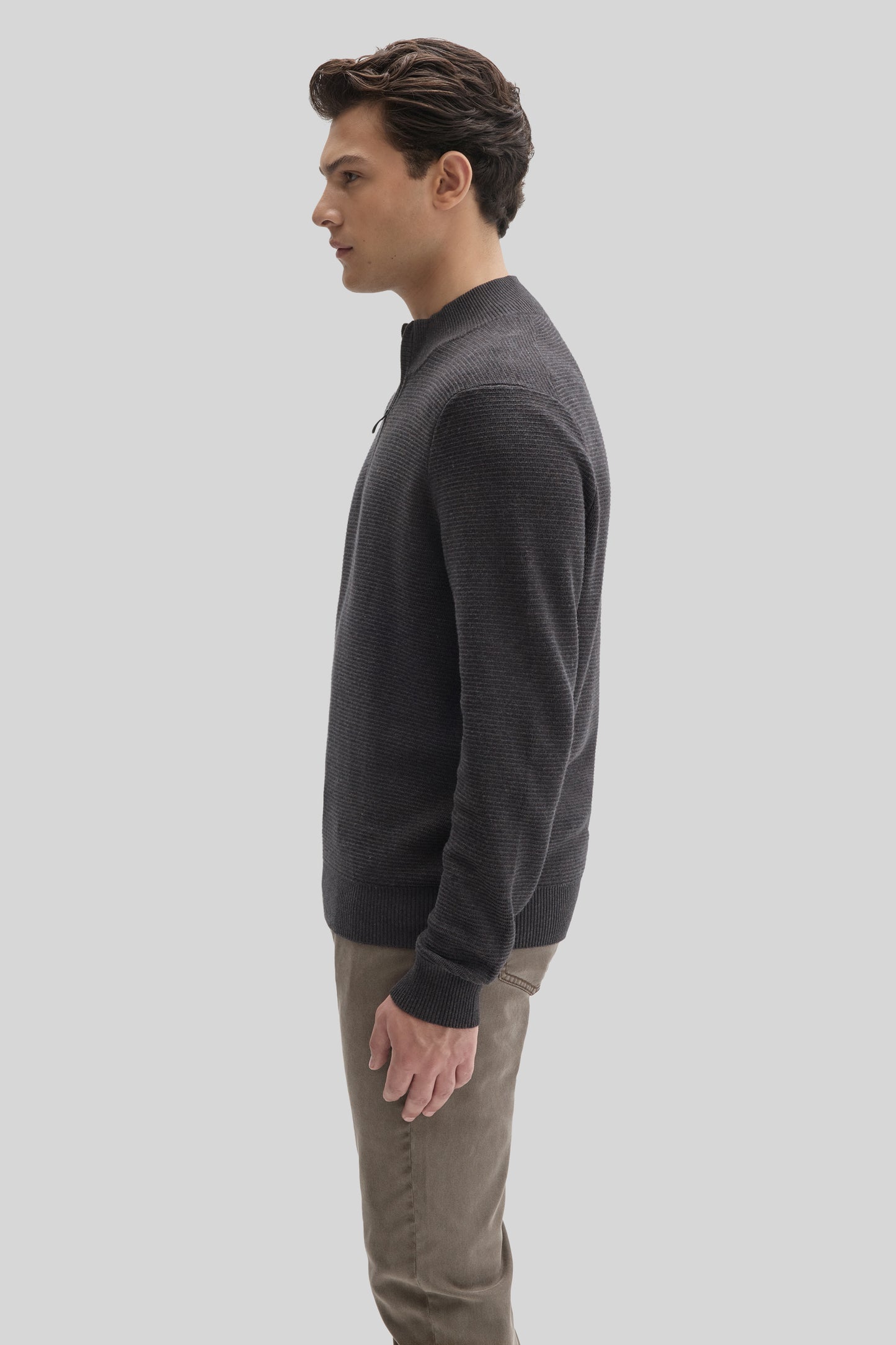 Man wearing charcoal quarter zip sweater with ribbed texture and tan pants, shown in side profile.