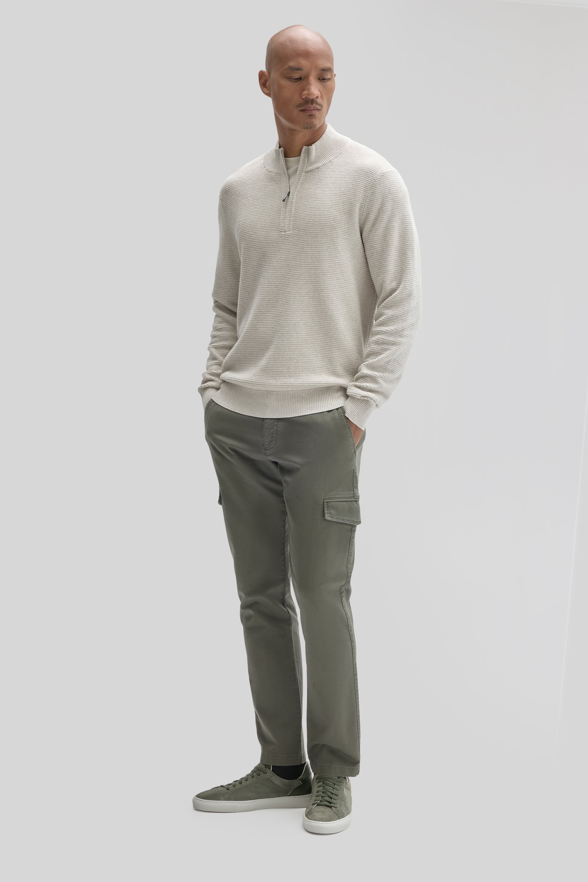 Cream quarter-zip sweater with ribbed texture worn with olive cargo pants and green sneakers.