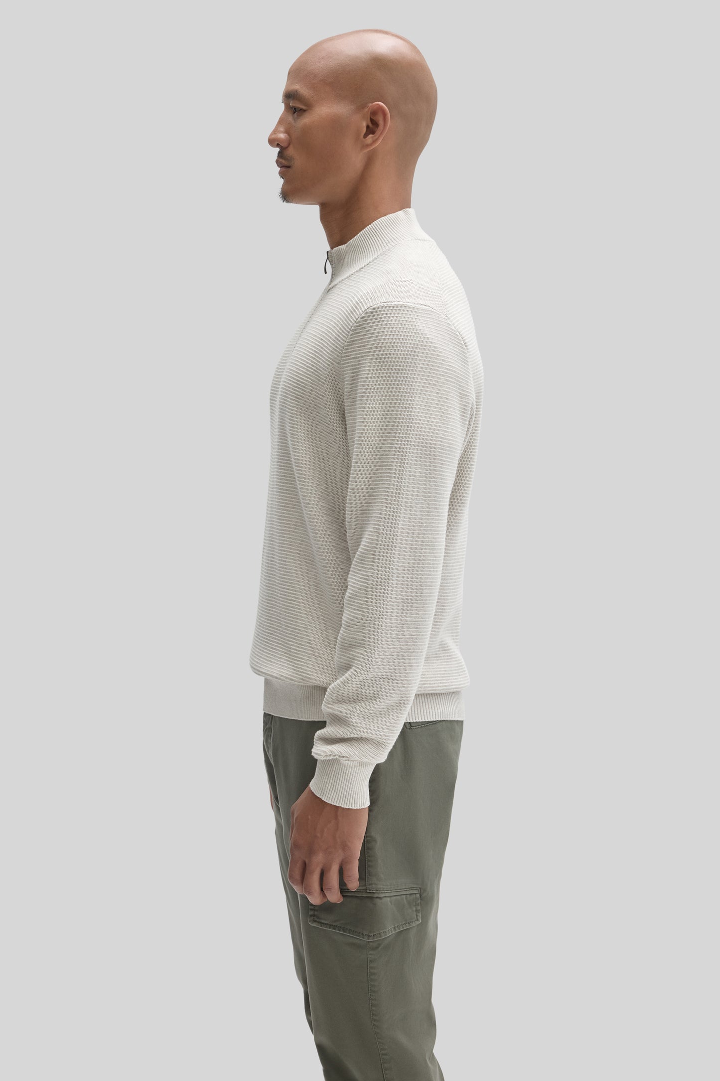 Cream ribbed quarter zip sweater worn with olive cargo pants, shown in profile view.