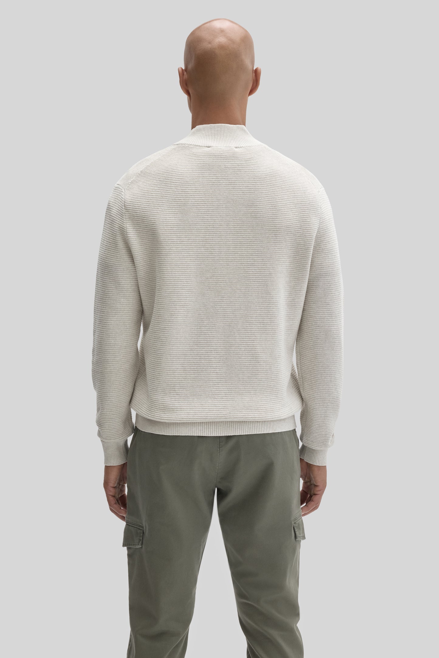 Cream ribbed quarter zip sweater worn with olive cargo pants, shown from back view on male model.