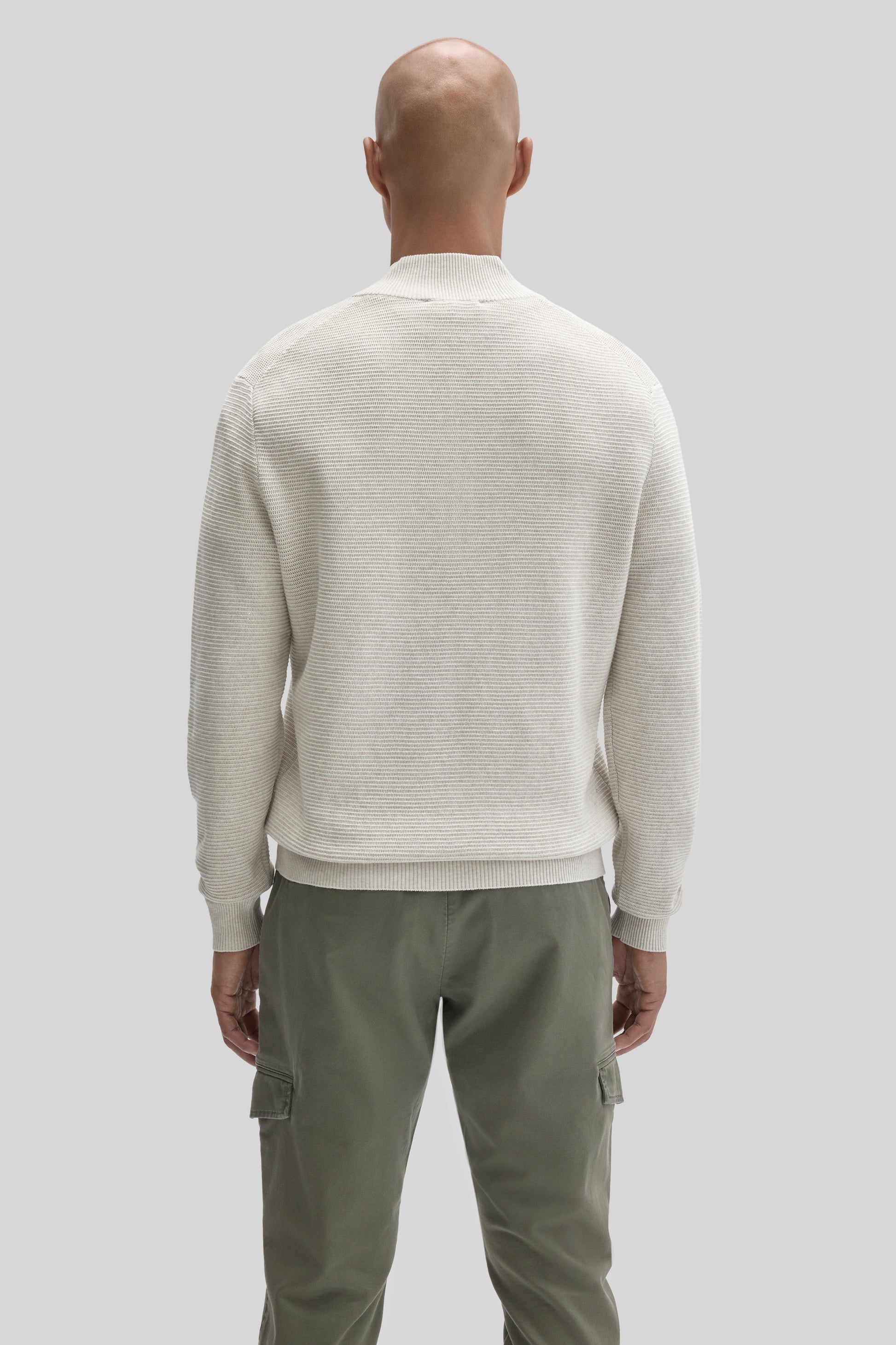 Cream ribbed quarter zip sweater worn with olive cargo pants, shown from back view on male model.