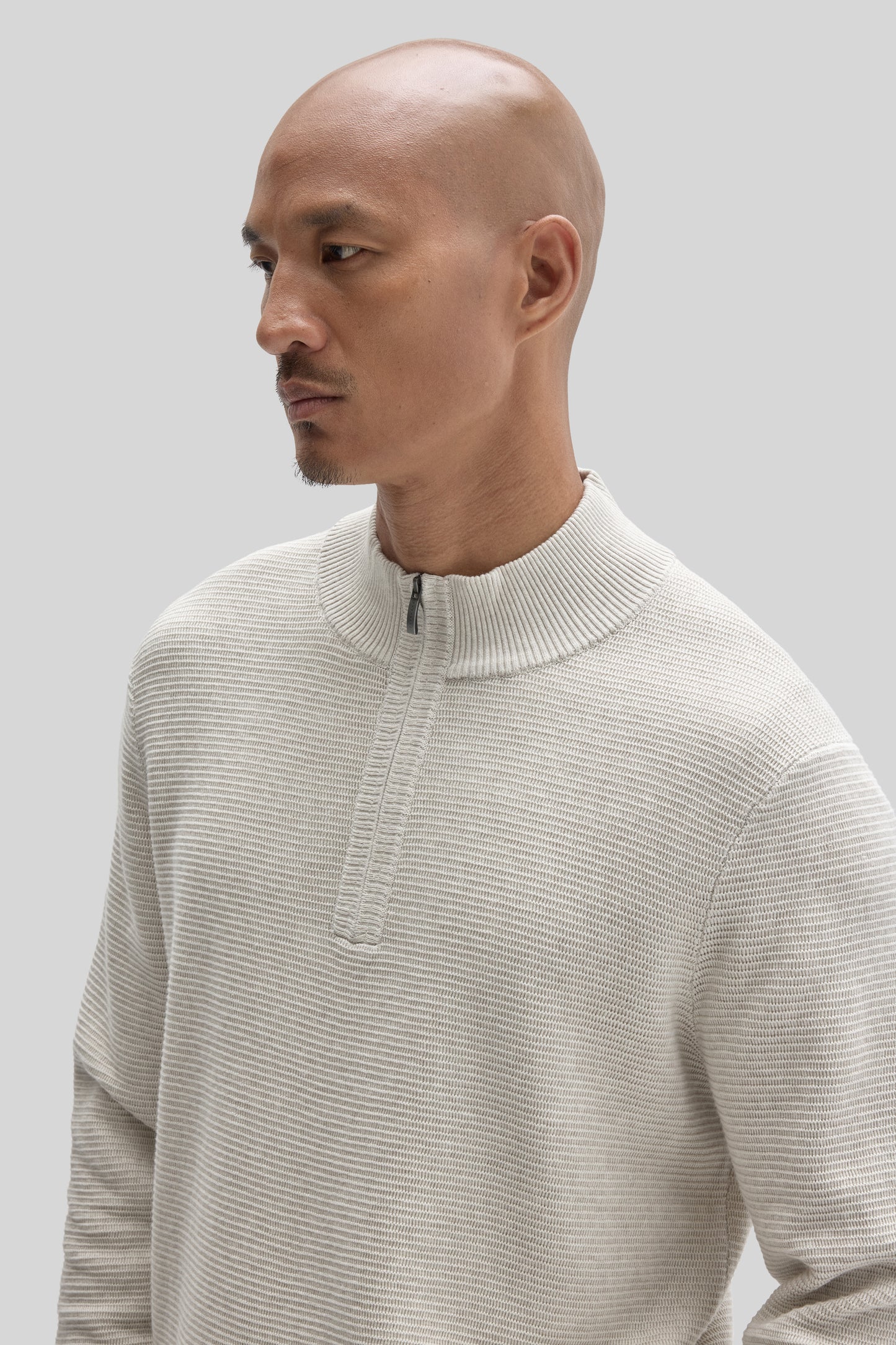 Cream ribbed quarter-zip sweater with mock neck worn by model shown in profile view.