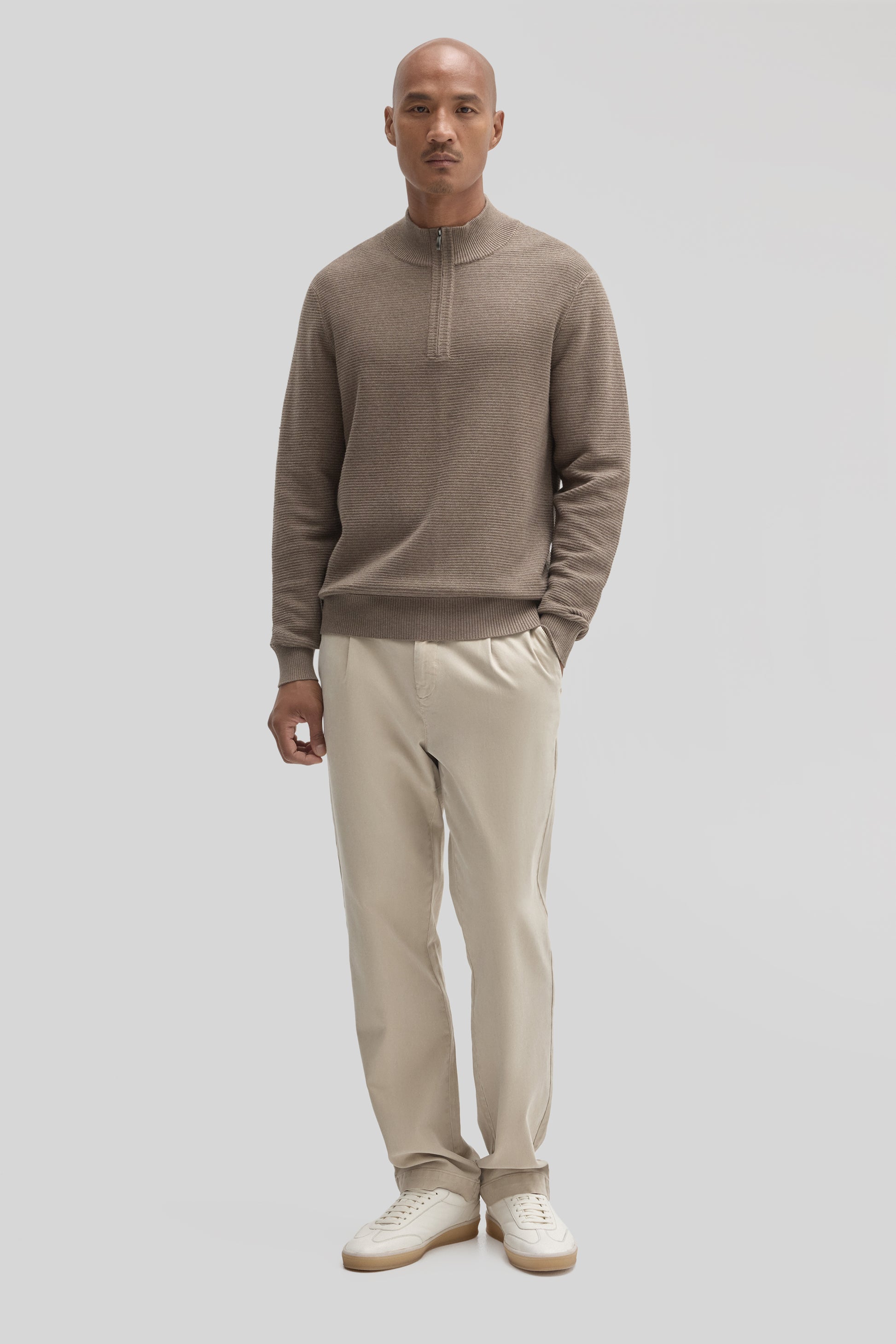 Man wearing taupe quarter-zip sweater with ribbed texture and cream chinos.