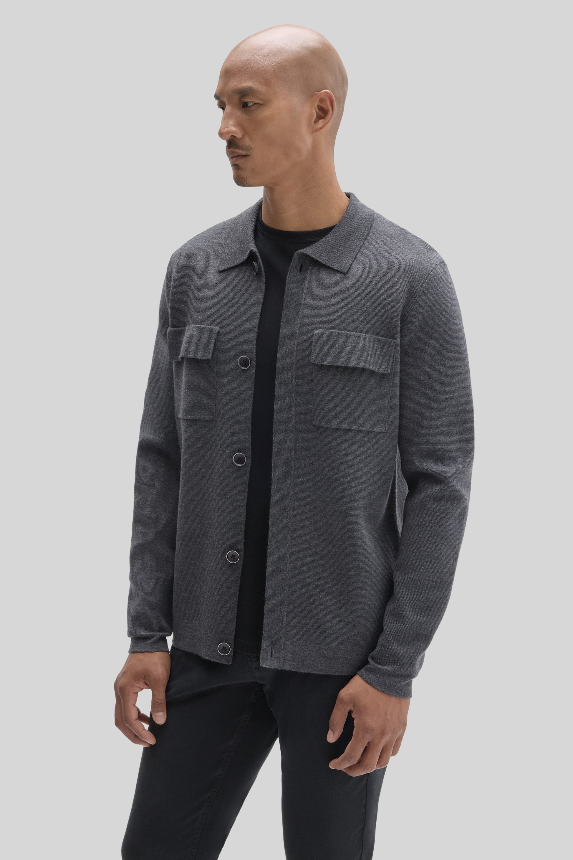 Charcoal gray buttoned cardigan with chest pockets worn over a black shirt.