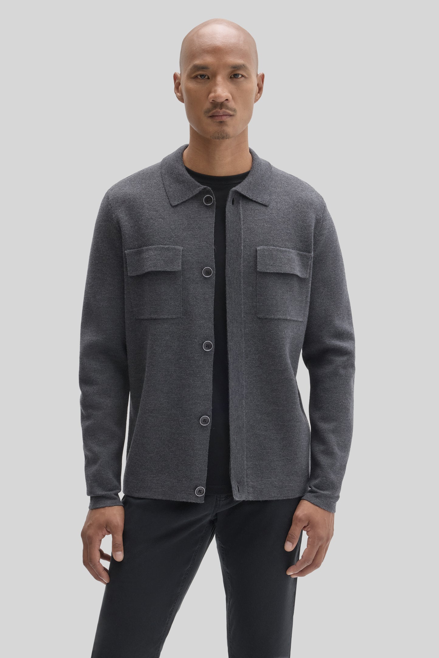 Charcoal gray buttoned cardigan with chest pockets worn over a black shirt.