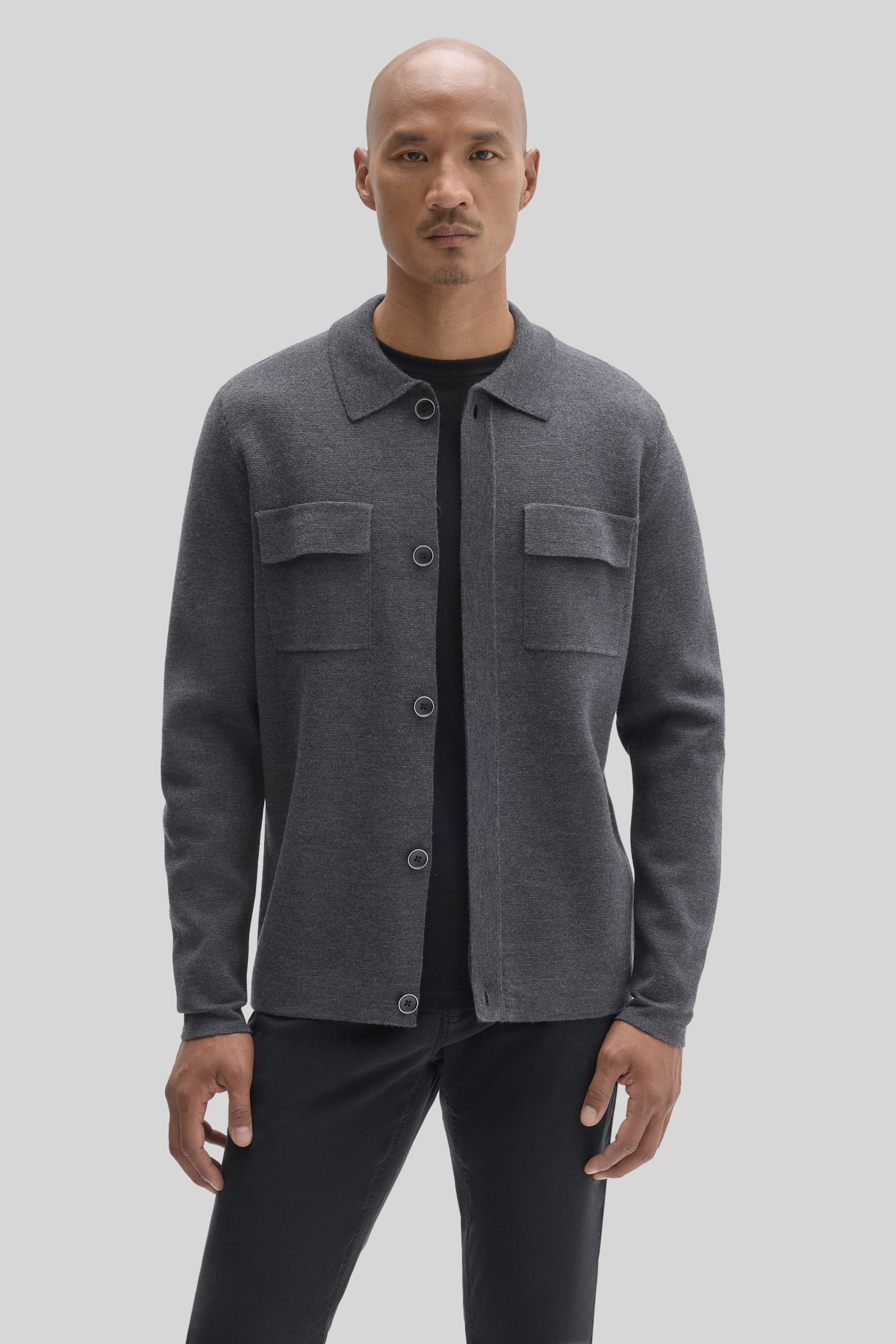 Charcoal gray buttoned cardigan with chest pockets worn over a black shirt.