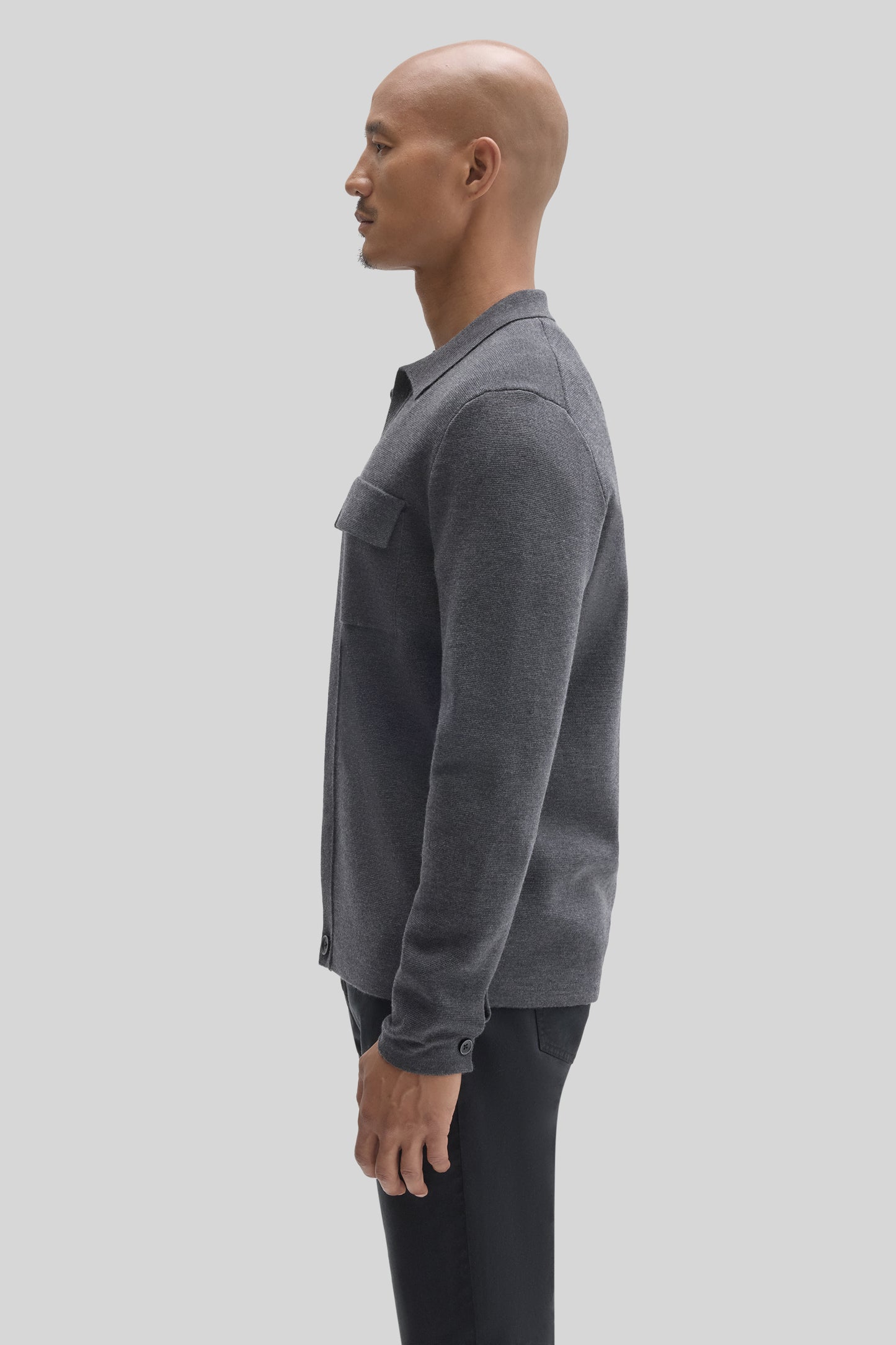 Charcoal gray buttoned cardigan with chest pocket, worn unbuttoned over black pants.