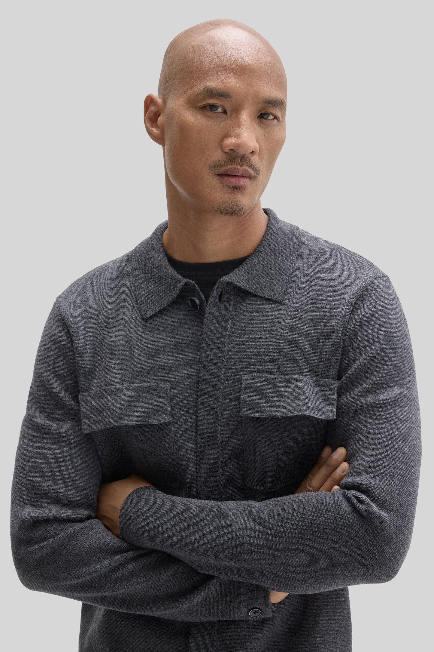 Charcoal gray cardigan with button front, collared neckline, and chest pockets worn by a man.