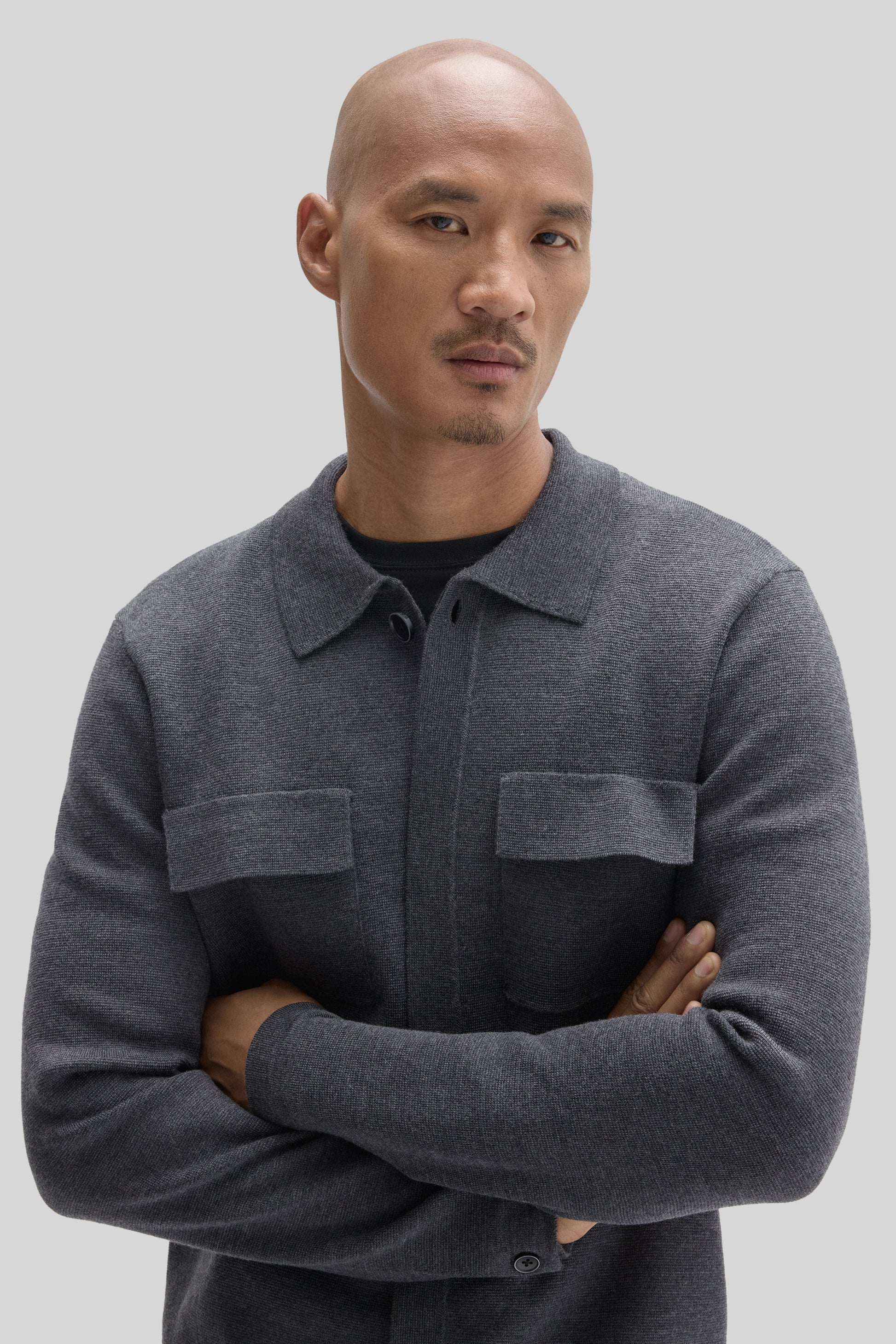 Charcoal gray cardigan with button front, collared neckline, and chest pockets worn by a man.