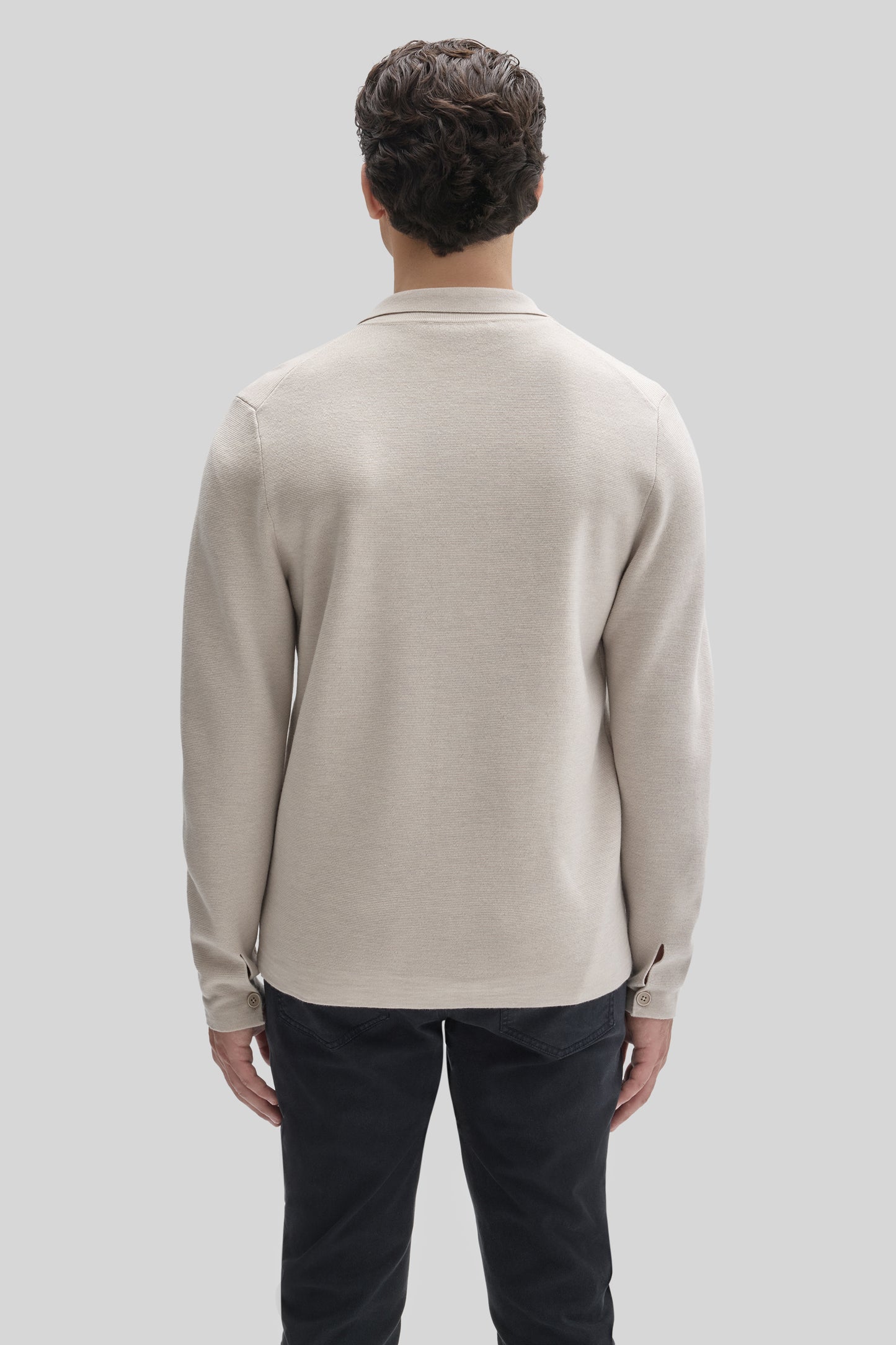 Beige buttoned cardigan with collar and long sleeves, shown from back on model wearing dark pants.
