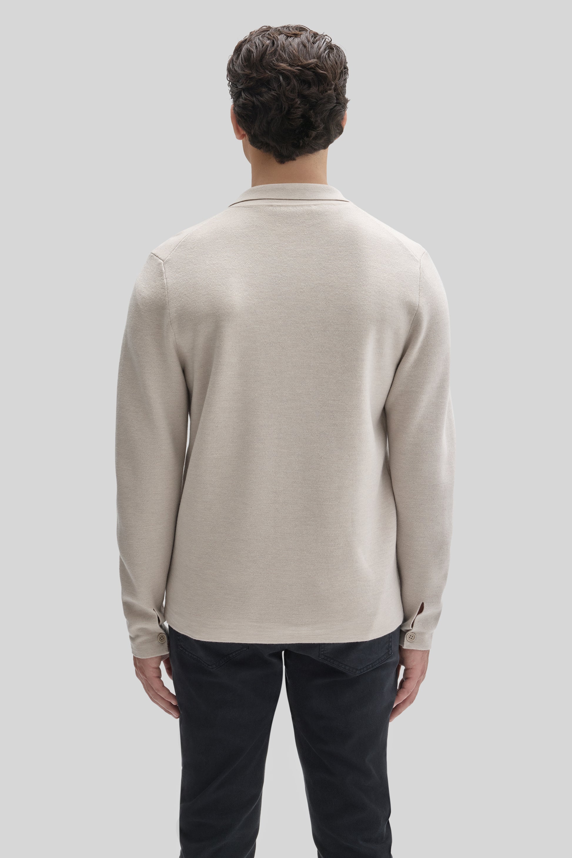 Beige buttoned cardigan with collar and long sleeves, shown from back on model wearing dark pants.