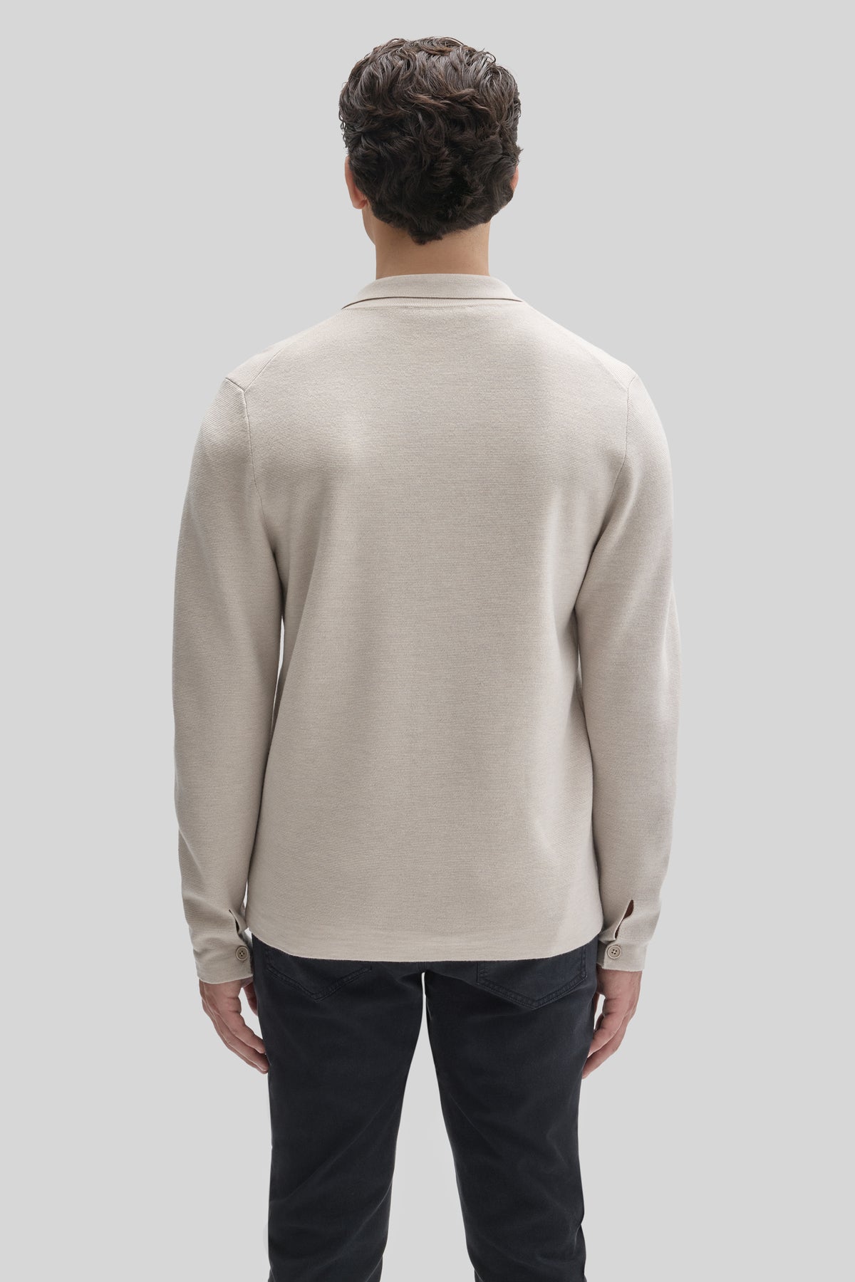 Beige buttoned cardigan with collar and long sleeves, shown from back on model wearing dark pants.