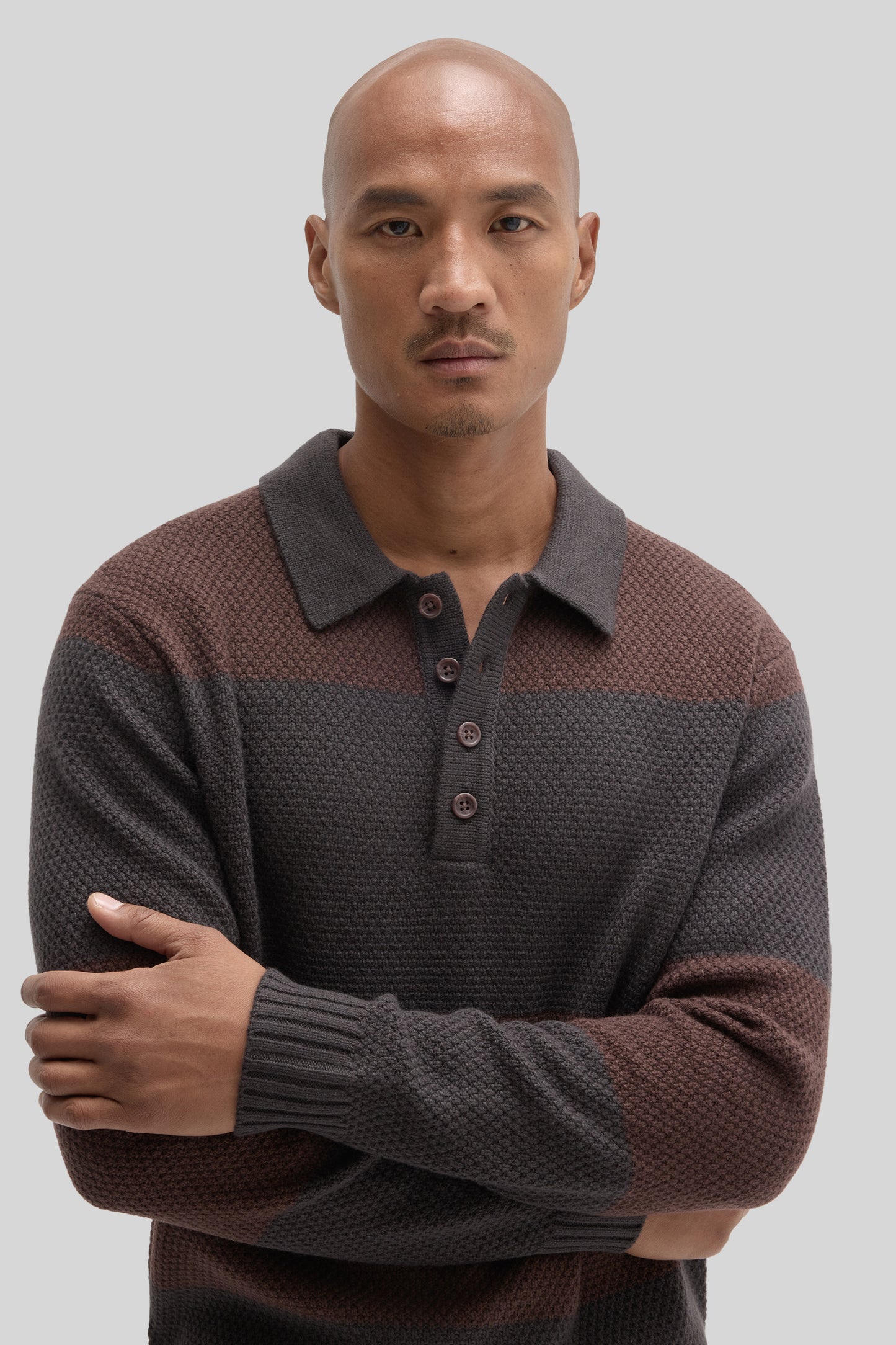 Brown and gray rugby polo sweater with textured knit fabric, collar, and button front worn by male model.