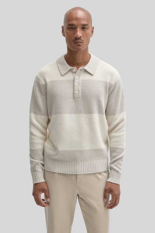 Cream rugby polo sweater with textured knit fabric, collar, and button placket worn with beige pants.