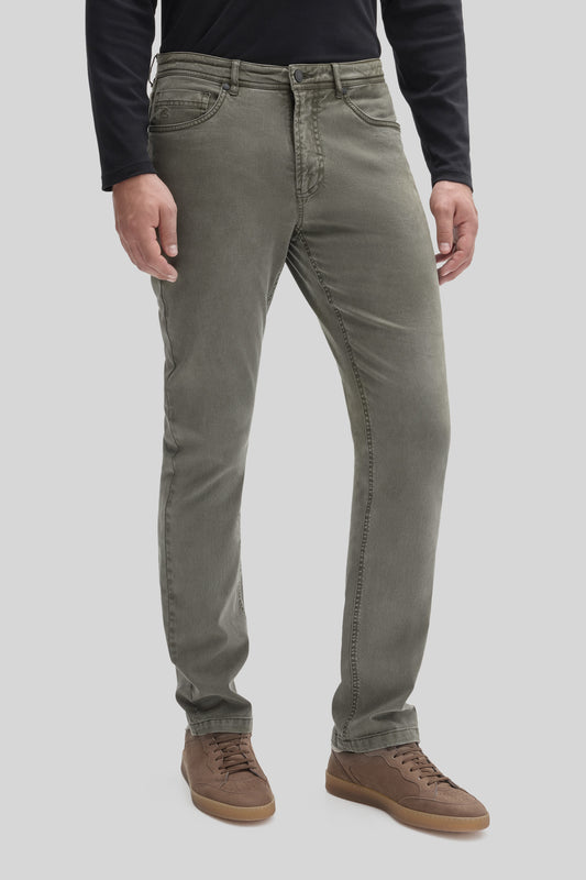 Khaki five-pocket stretch pants with button fly on model wearing black long-sleeve shirt and brown lace-up boots.
