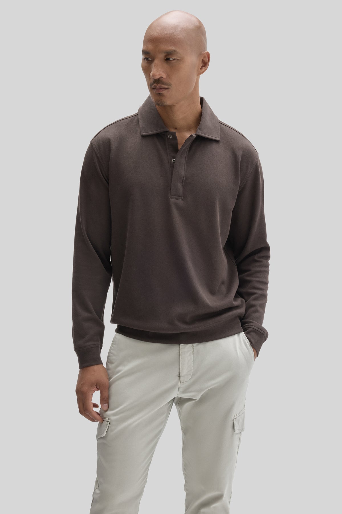 Man wearing charcoal long-sleeve polo shirt with snap front and cream cargo pants with side pockets.