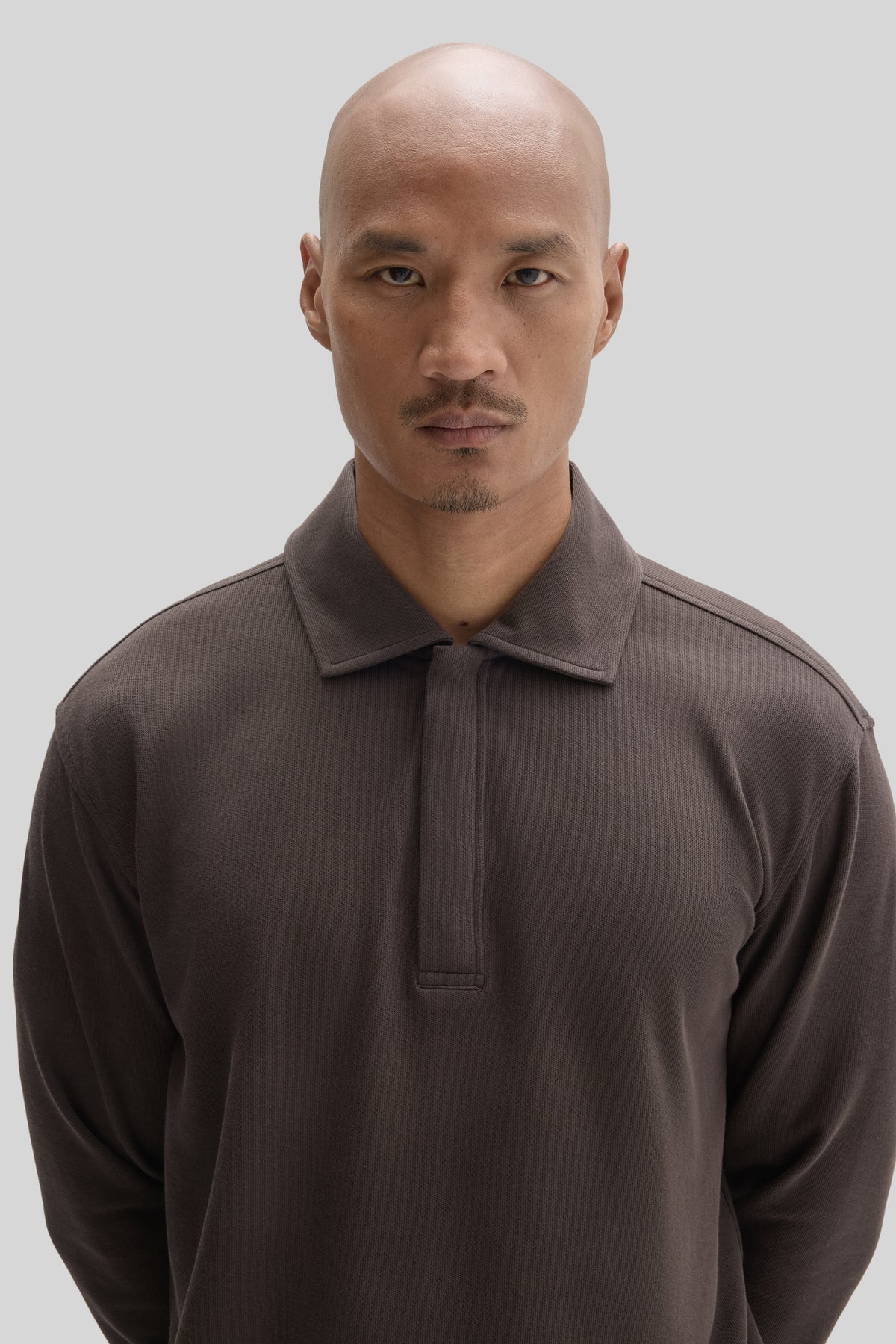 Man wearing a charcoal gray polo shirt with a snap front closure and collar.