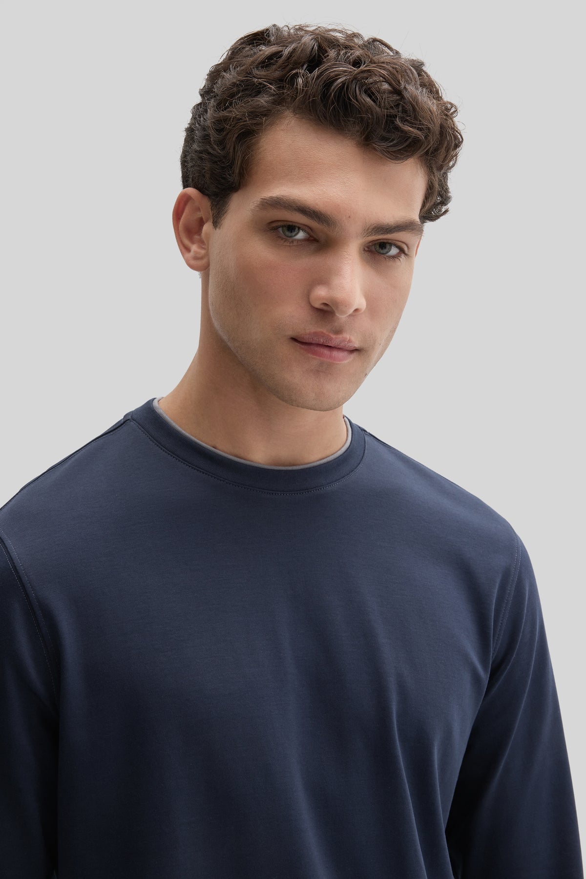 Man wearing navy blue long sleeve crewneck tee with double neck detail.