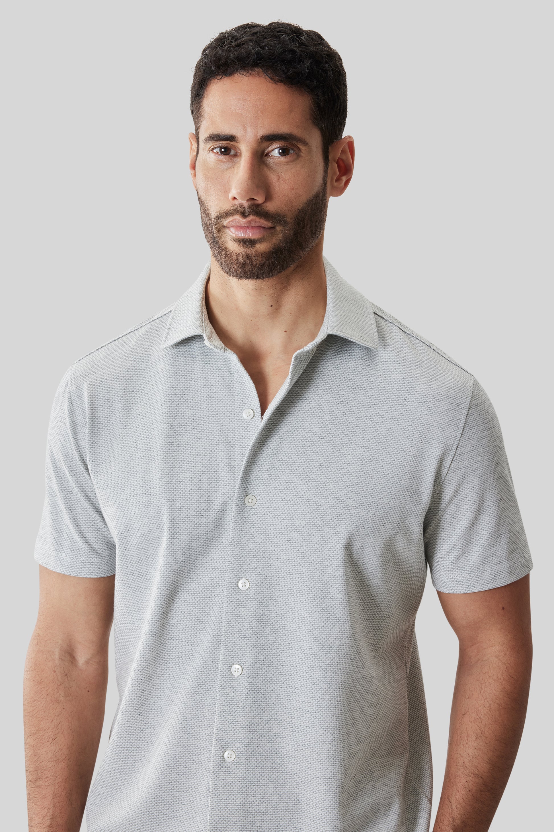 Man wearing light gray short-sleeve knit shirt with textured fabric and white button front closure.