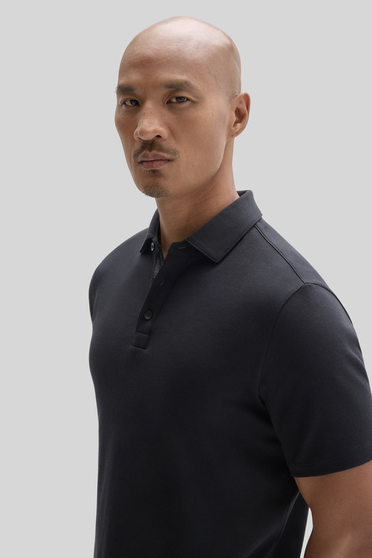 Man wearing dark navy herringbone polo shirt with collar and button placket.