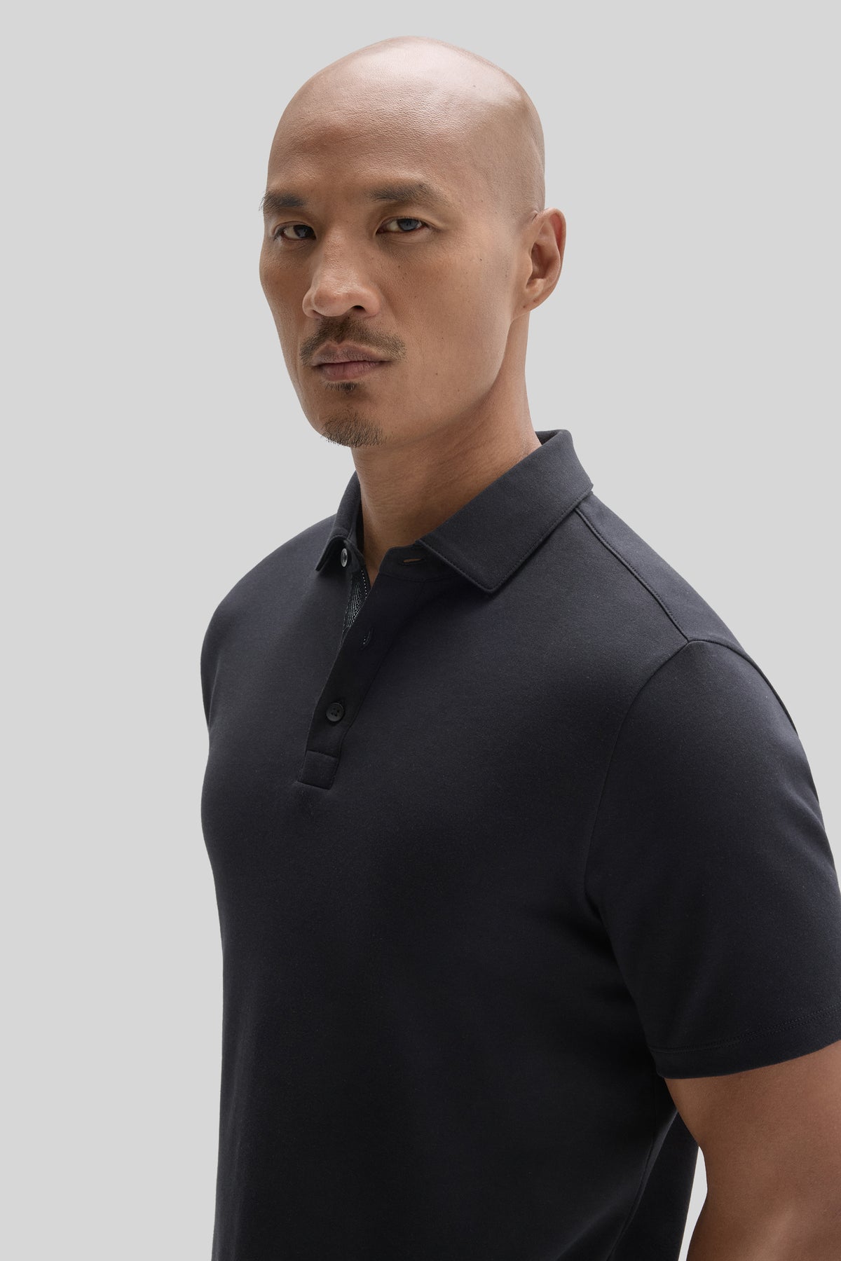 Man wearing dark navy herringbone polo shirt with collar and button placket.