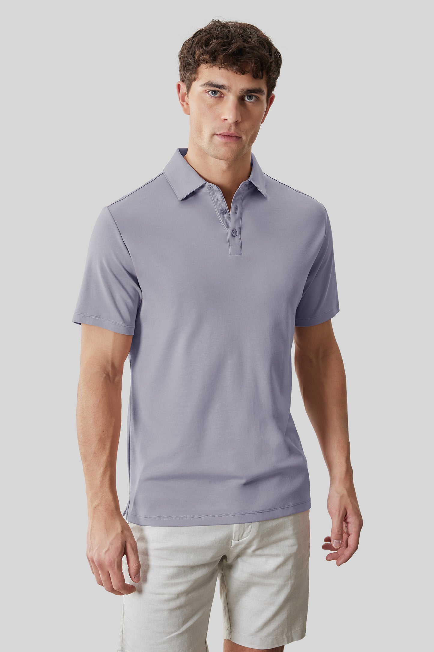 Man wearing a lavender herringbone polo shirt with short sleeves and a collared neckline.