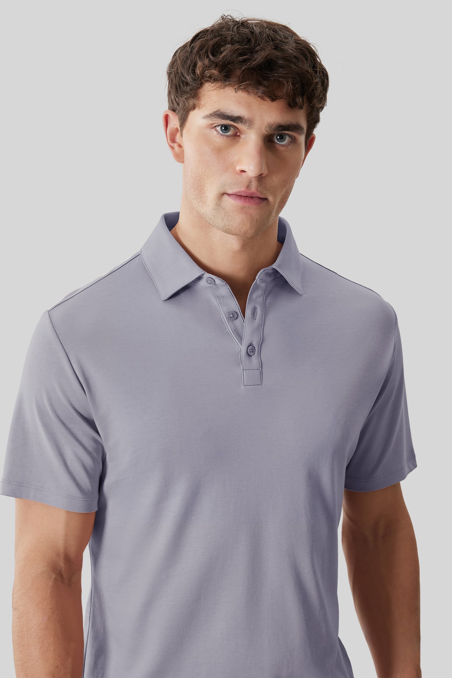 Man wearing lavender short-sleeve polo shirt with herringbone pattern placket detail.
