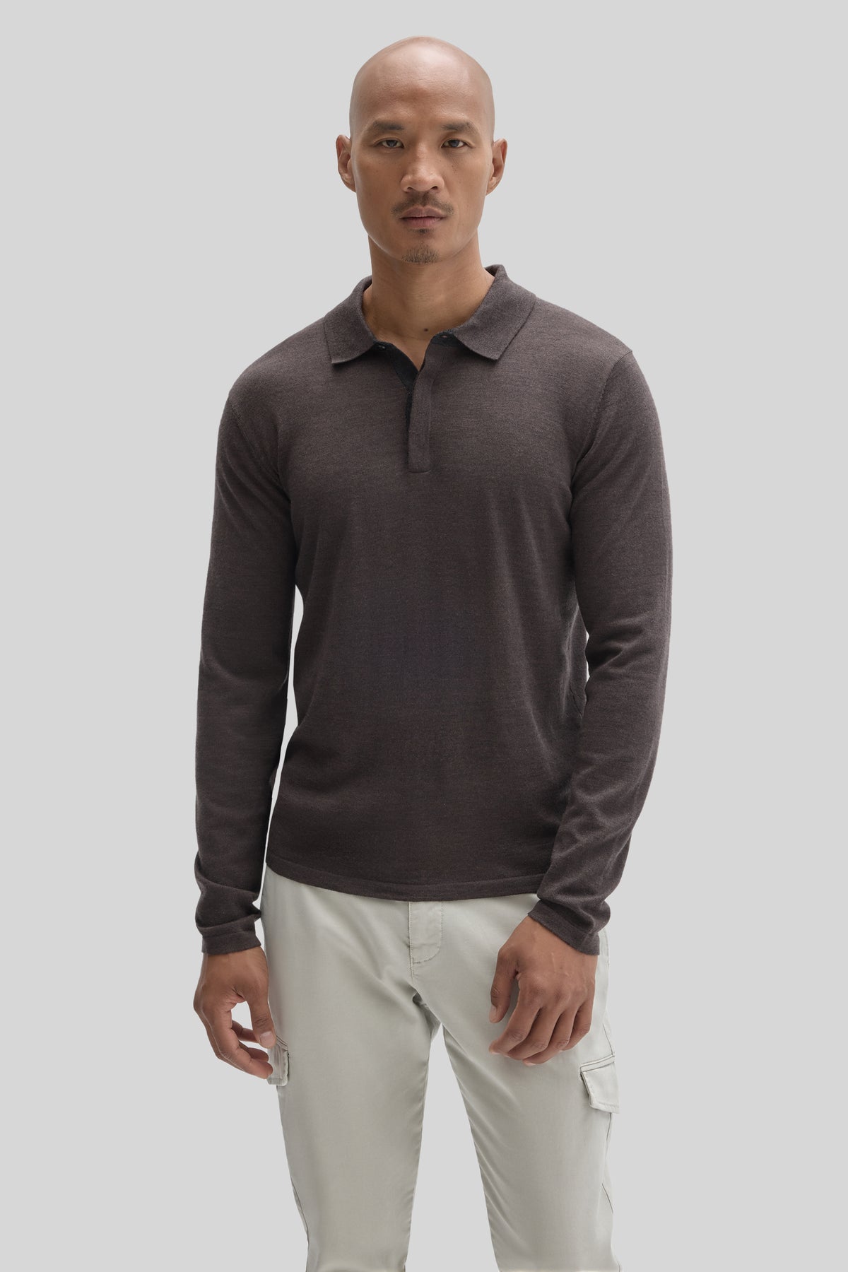 Man wearing dark charcoal long-sleeve polo sweater with collar and cream cargo pants.