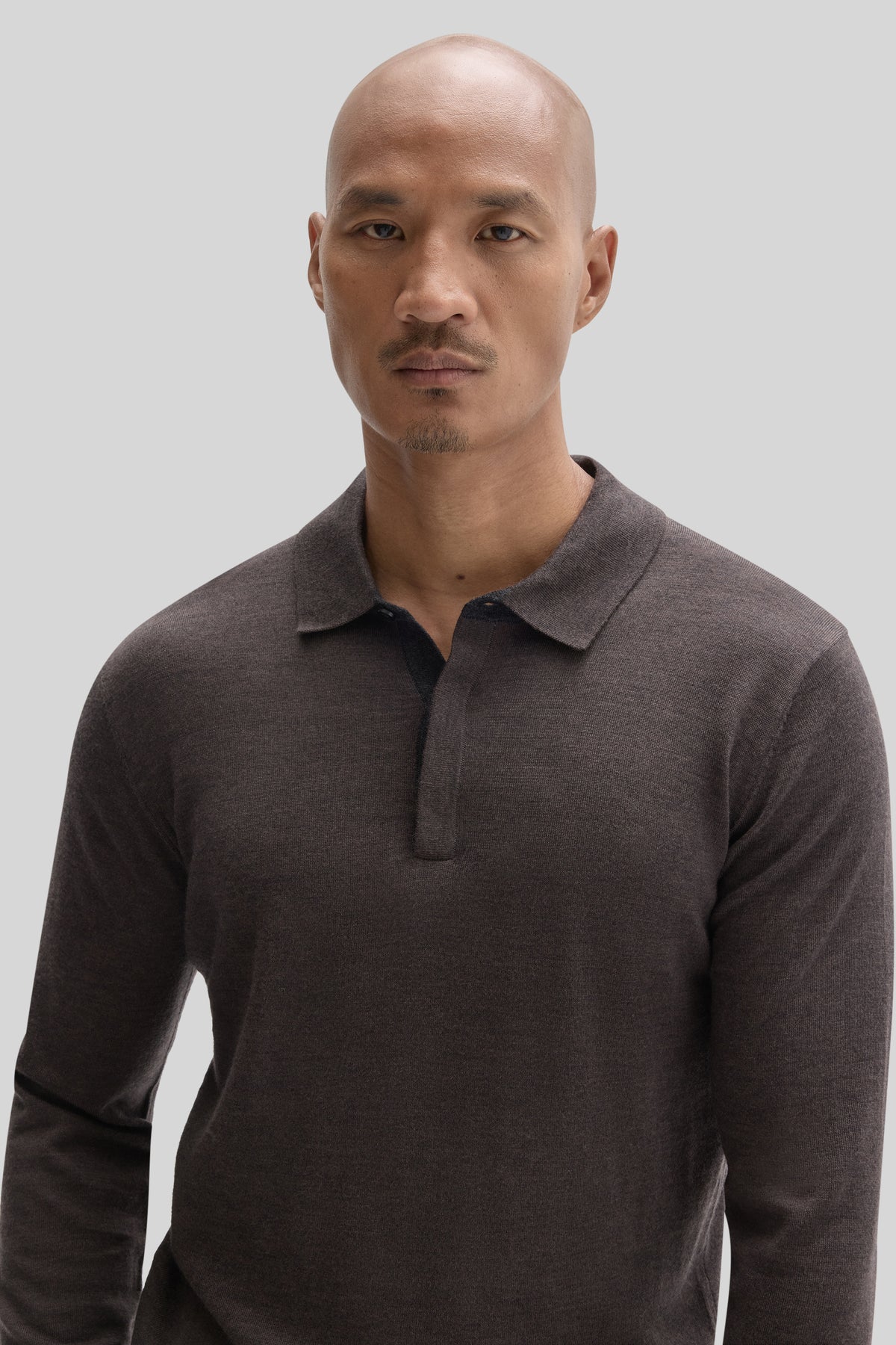Man wearing charcoal long sleeve sweater polo with collared neckline and partial button front.