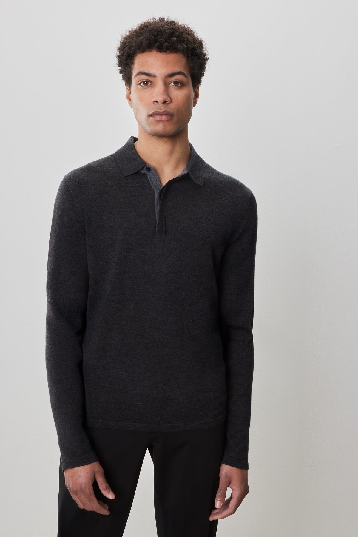Man wearing charcoal gray long-sleeve sweater polo with collar and half-button front.