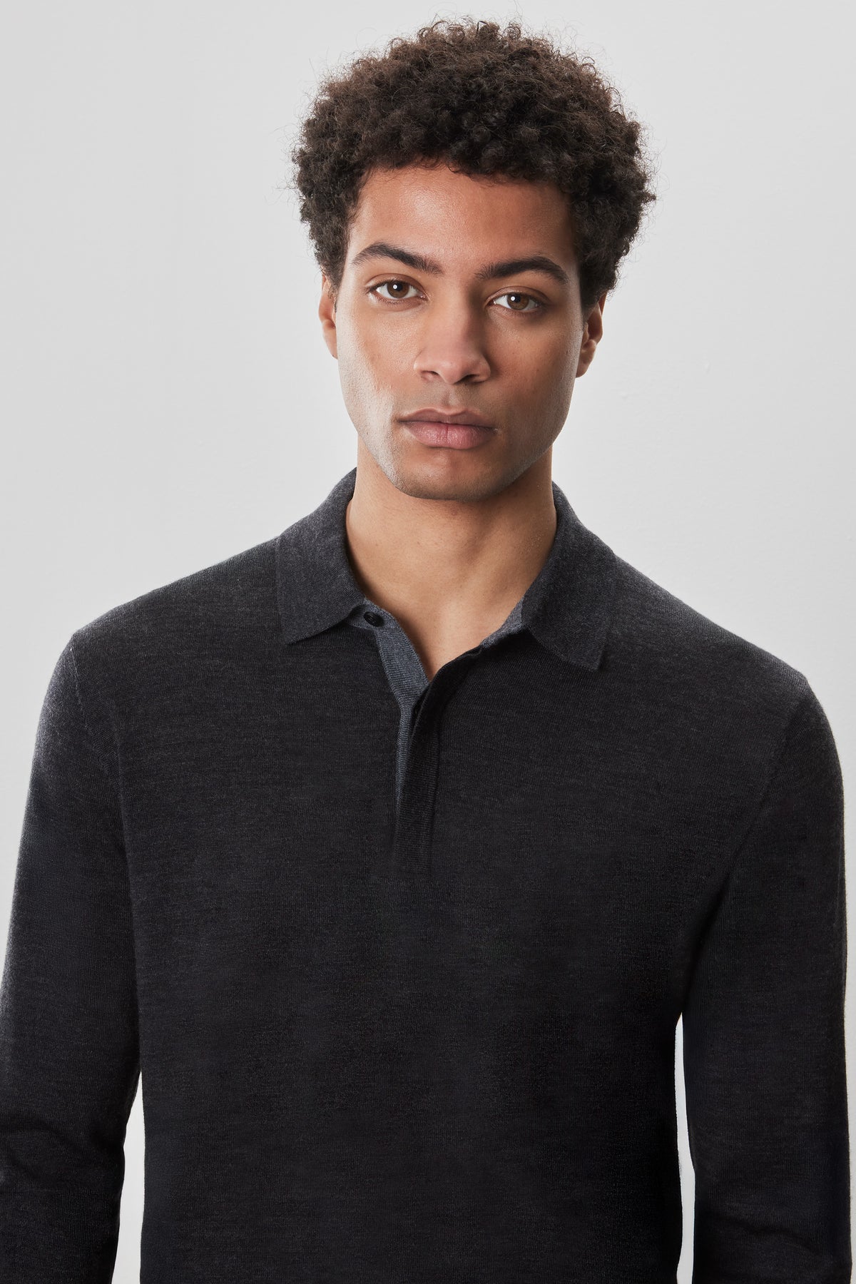 Man wearing dark charcoal long-sleeve sweater polo with button placket.