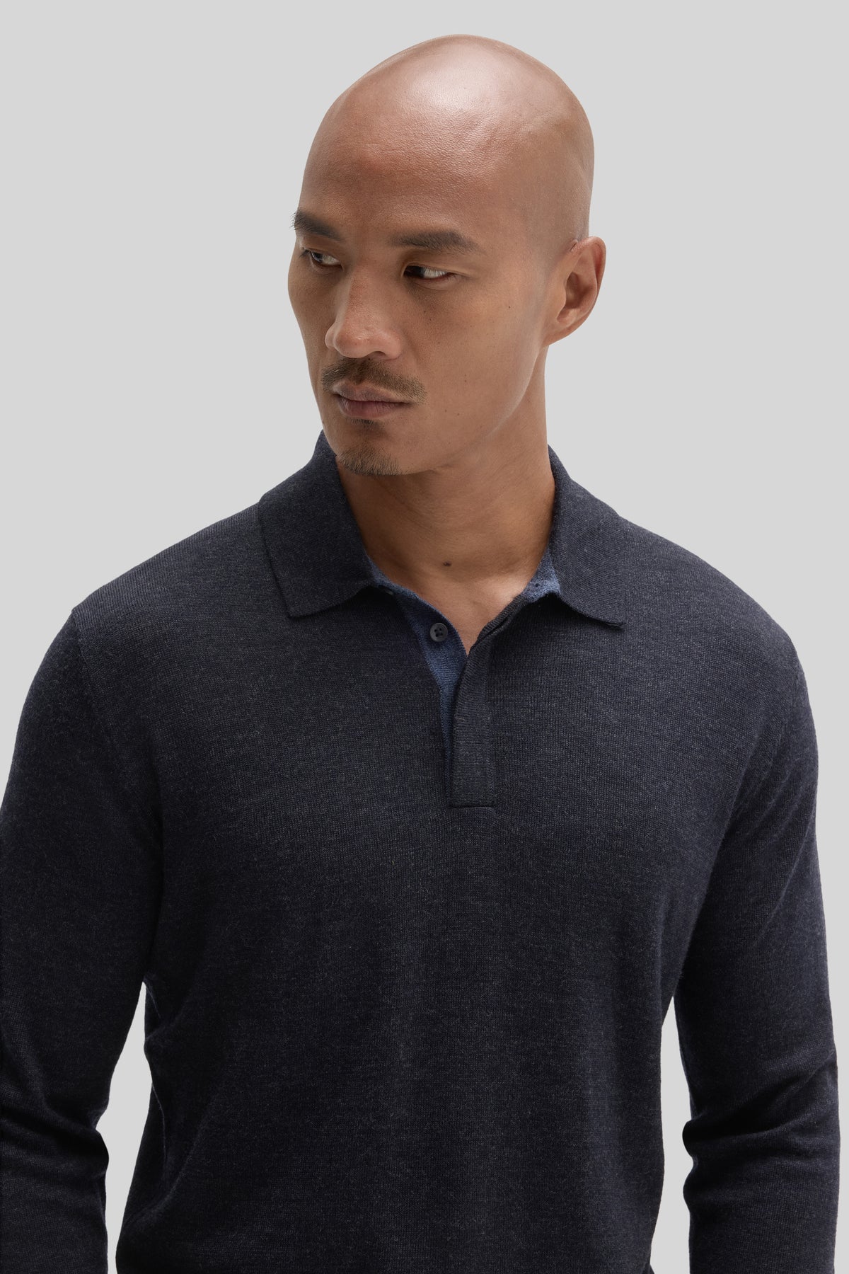 Man wearing dark navy long sleeve sweater polo with ribbed collar and button front.