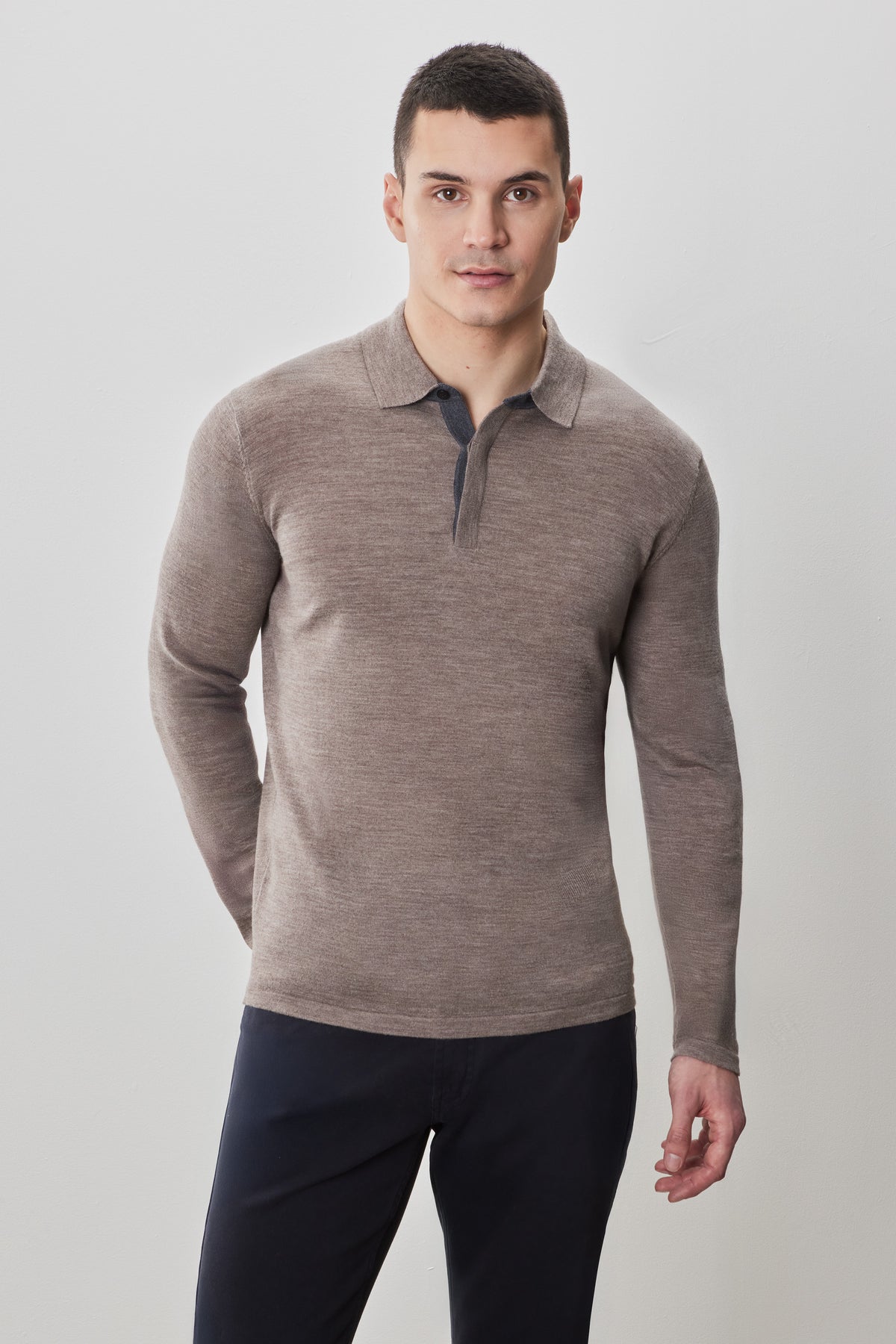 Men's long-sleeve polo sweater in taupe with collar and quarter-zip front, paired with dark navy trousers.