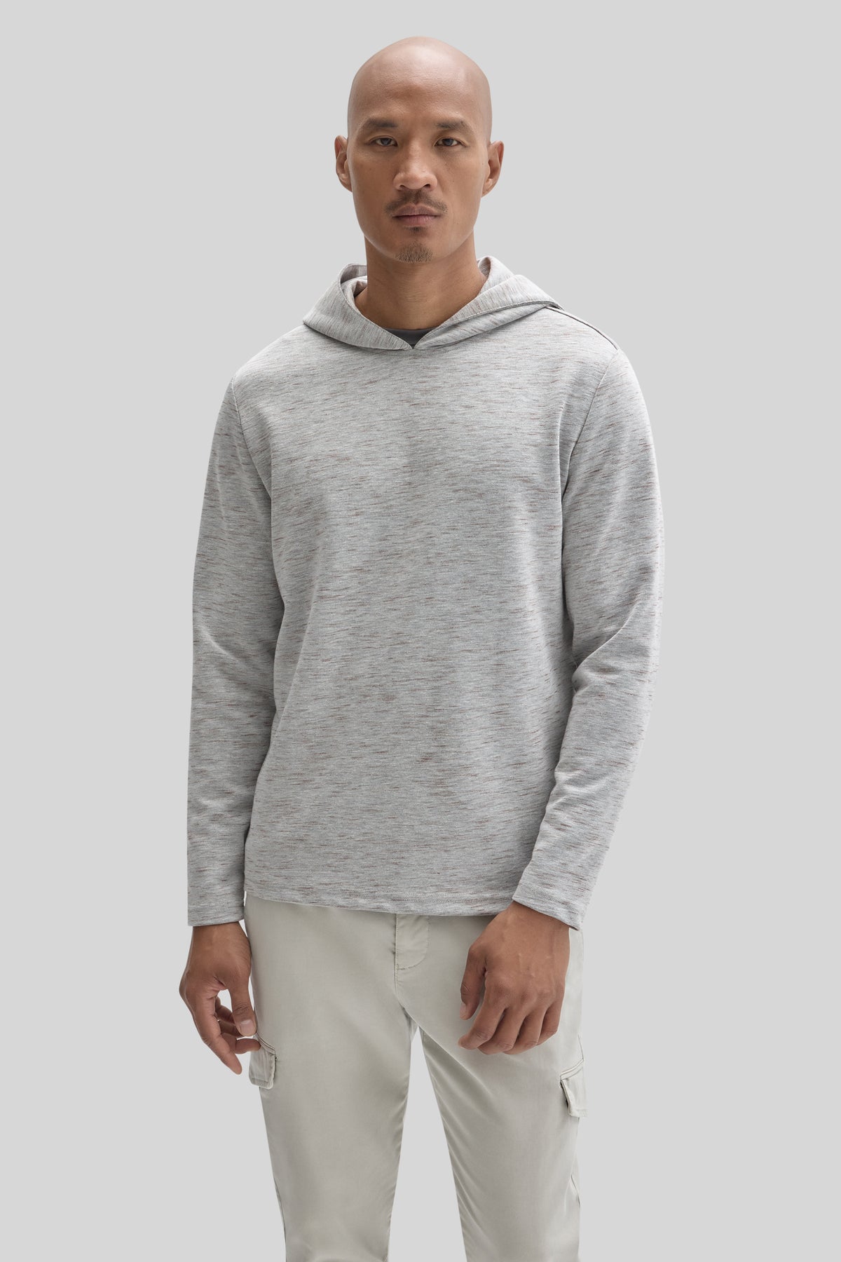 Man wearing light gray hoodie with hood and long sleeves, paired with cream cargo pants.
