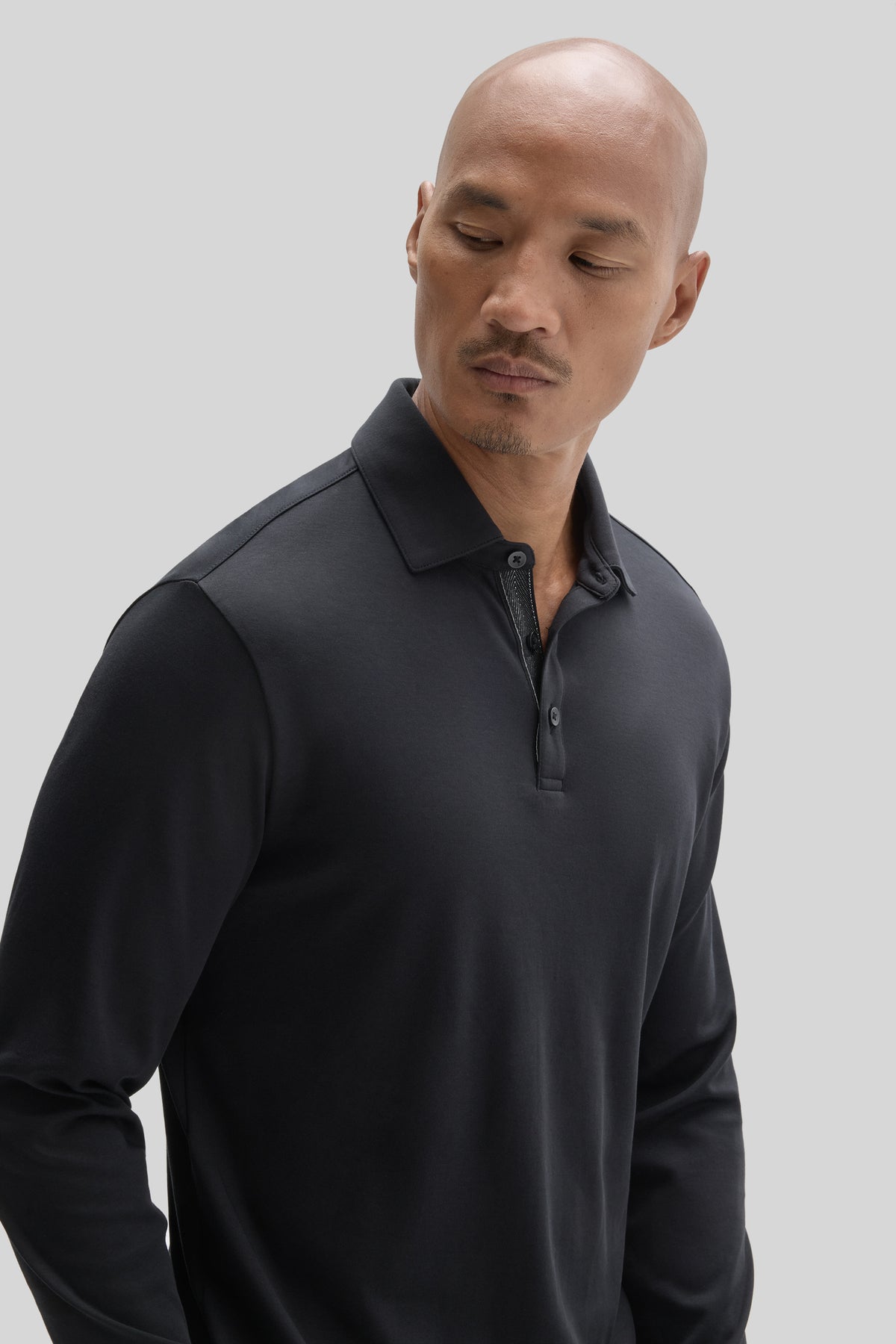 Man wearing a dark navy long-sleeve polo shirt with herringbone texture and button placket.
