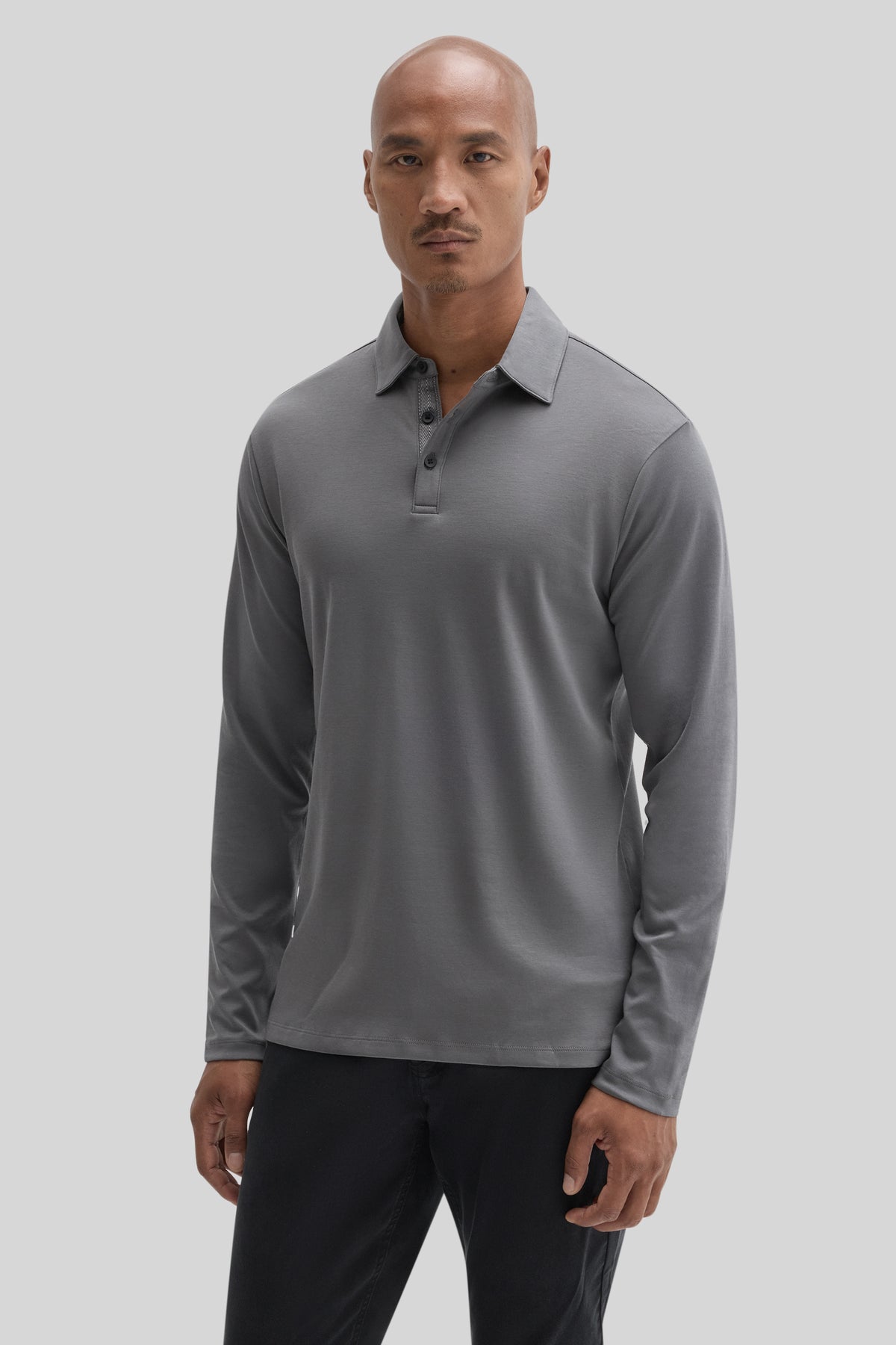 Gray long sleeve polo shirt with herringbone texture and button placket worn with black trousers.