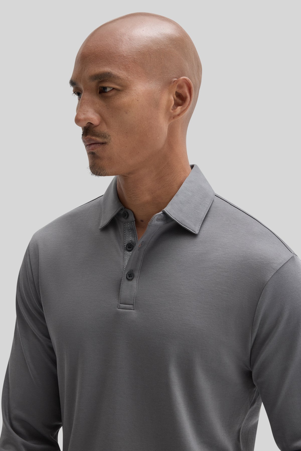 Gray long sleeve polo shirt with herringbone texture and button placket, shown on model in profile view.