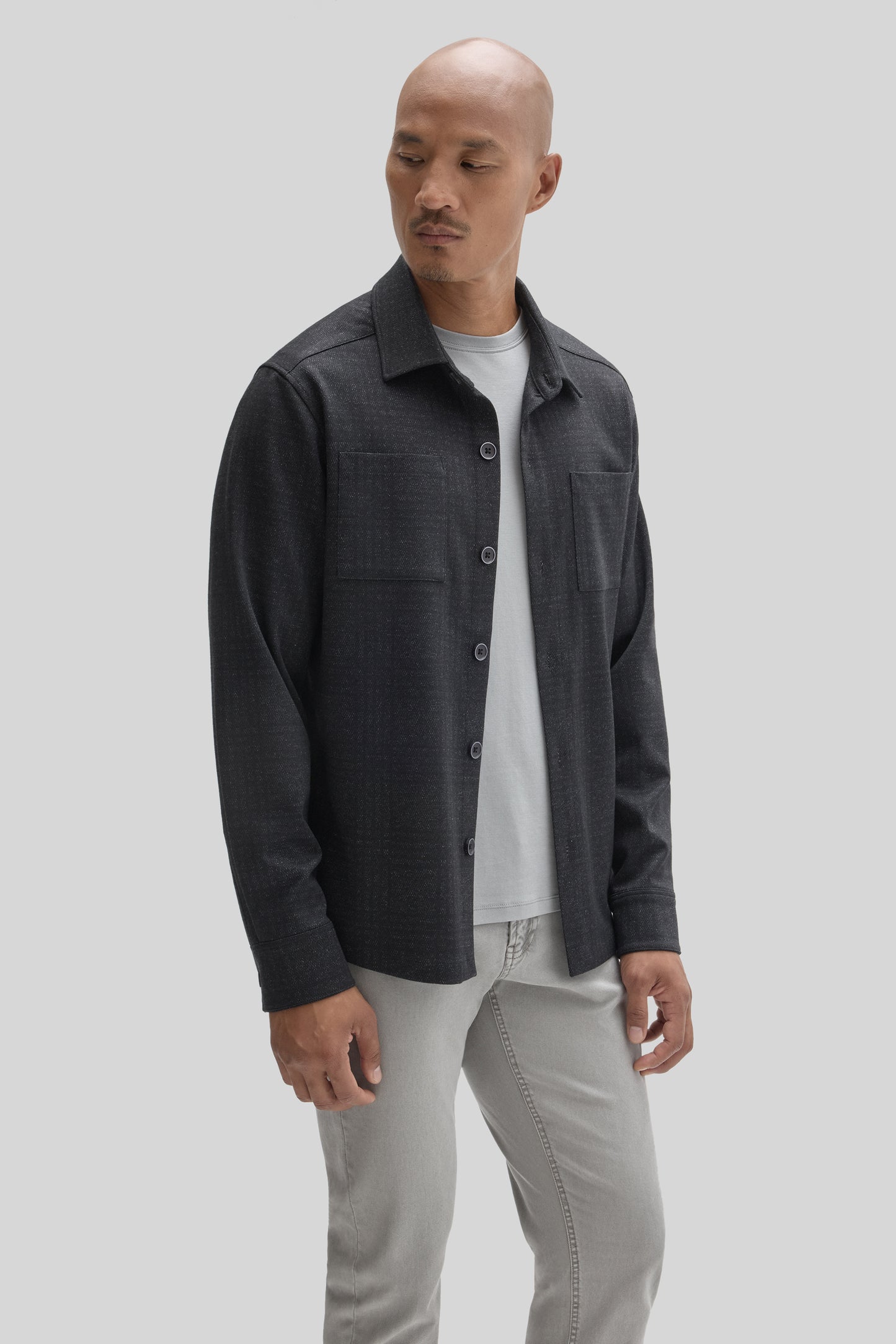 Charcoal gray overshirt with collar, button front, and chest pocket worn over white t-shirt and light jeans.