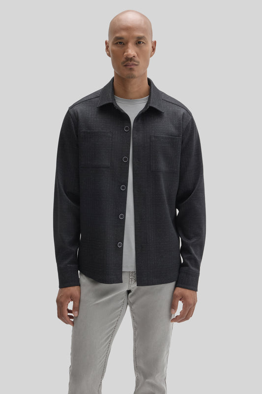 Man wearing charcoal overshirt with button front and chest pockets over light gray t-shirt and beige pants.