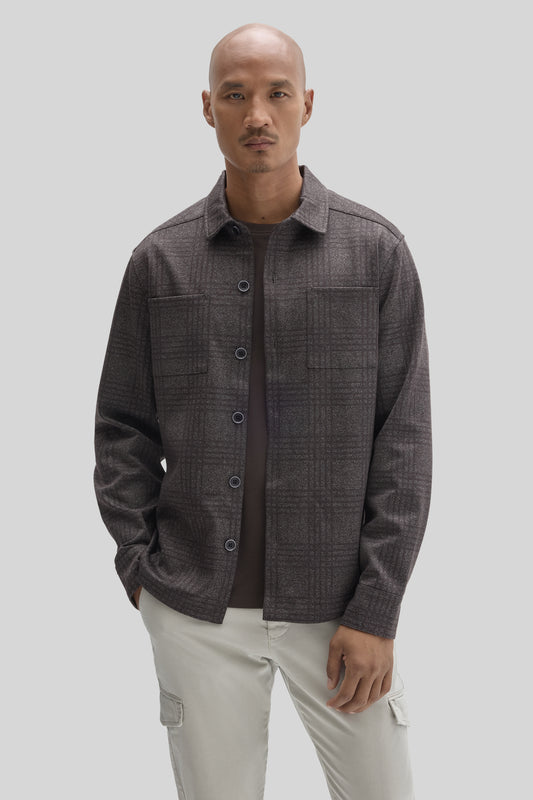 Man wearing charcoal gray button-up overshirt with chest pockets over dark undershirt and cream cargo pants.