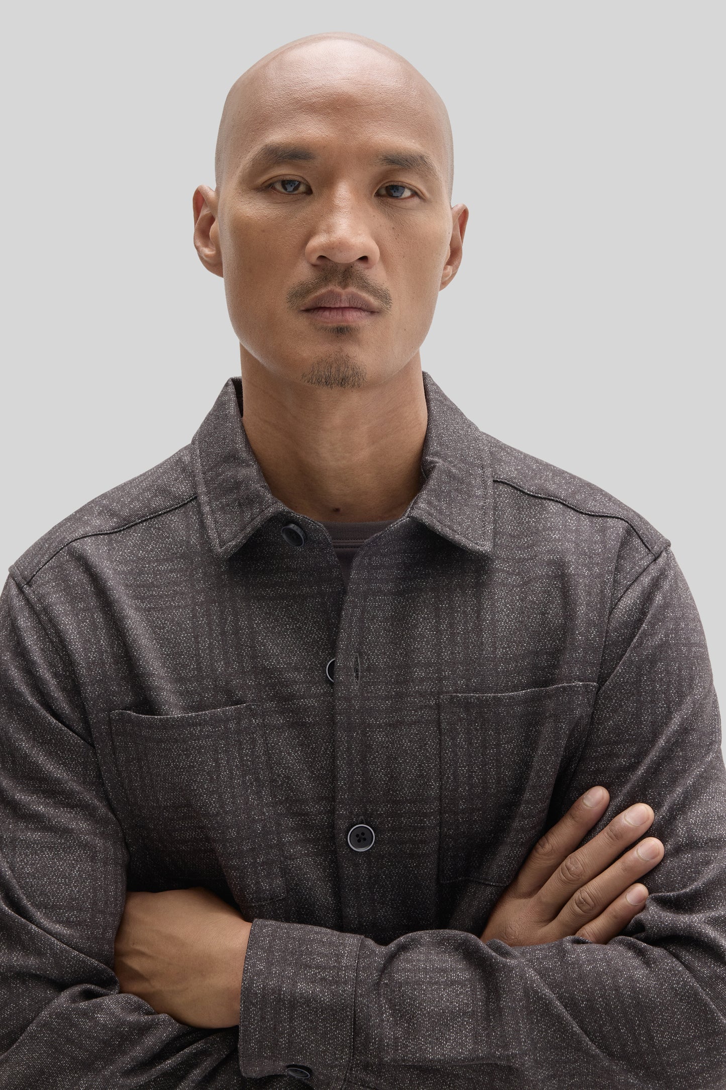 Charcoal gray overshirt with textured fabric, button front, and chest pockets worn by man against neutral background.