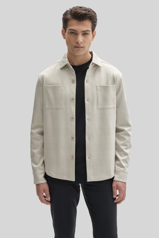 Cream overshirt with button front, chest pockets, and long sleeves worn over a black t-shirt.