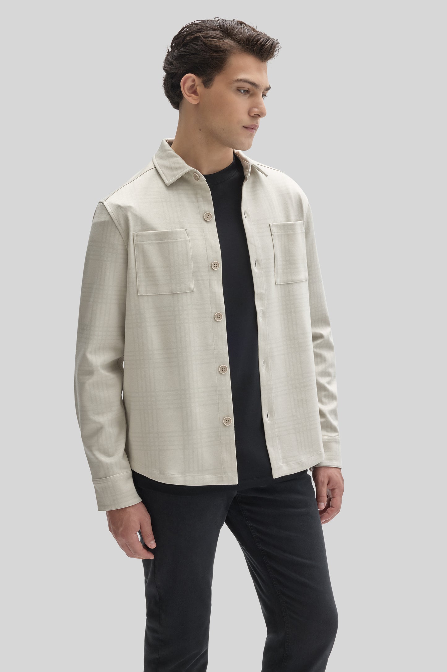 Cream overshirt with button front, collar, and chest pockets worn over a black t-shirt.