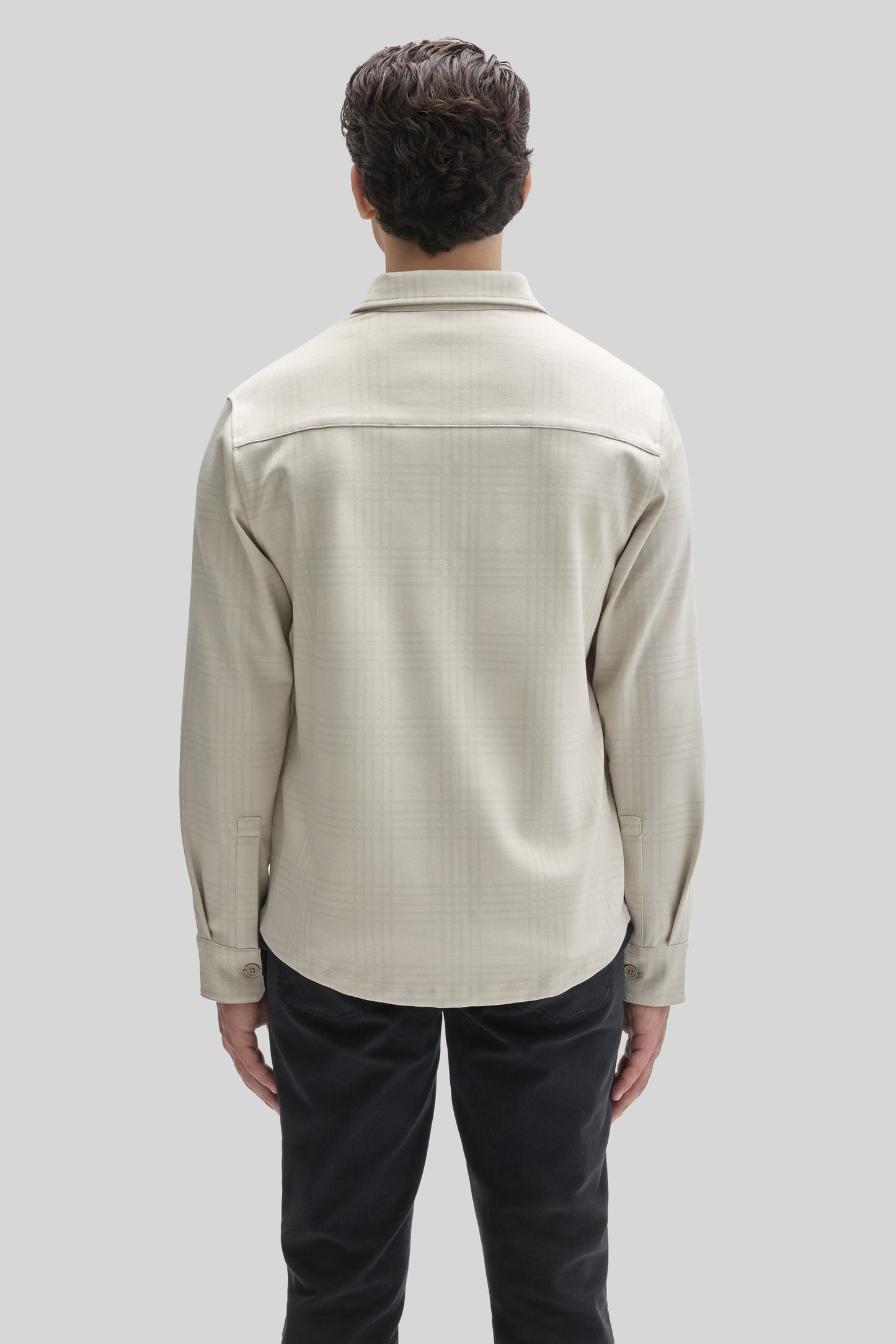 Beige overshirt with spread collar and long sleeves worn over black pants, shown from back view.