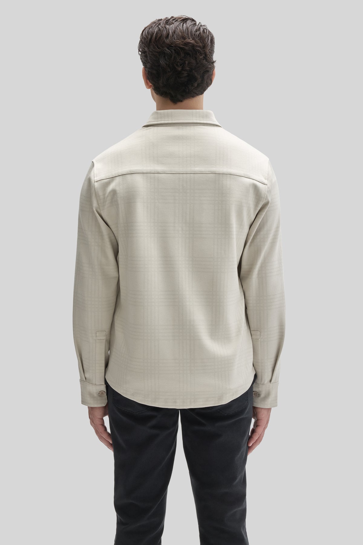 Beige overshirt with spread collar and long sleeves worn over black pants, shown from back view.