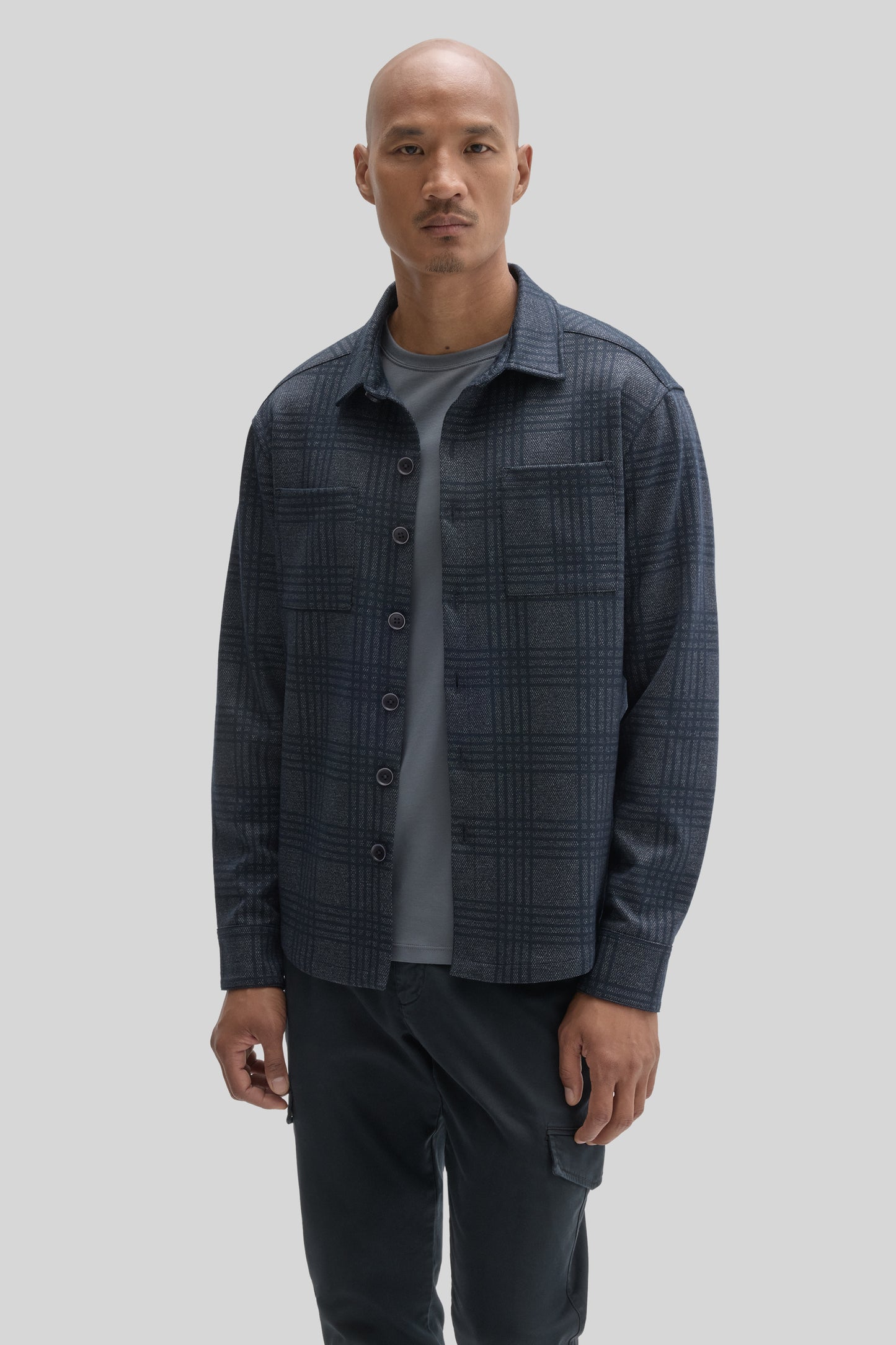 Dark blue plaid overshirt with button front, worn open over gray t-shirt and black pants.